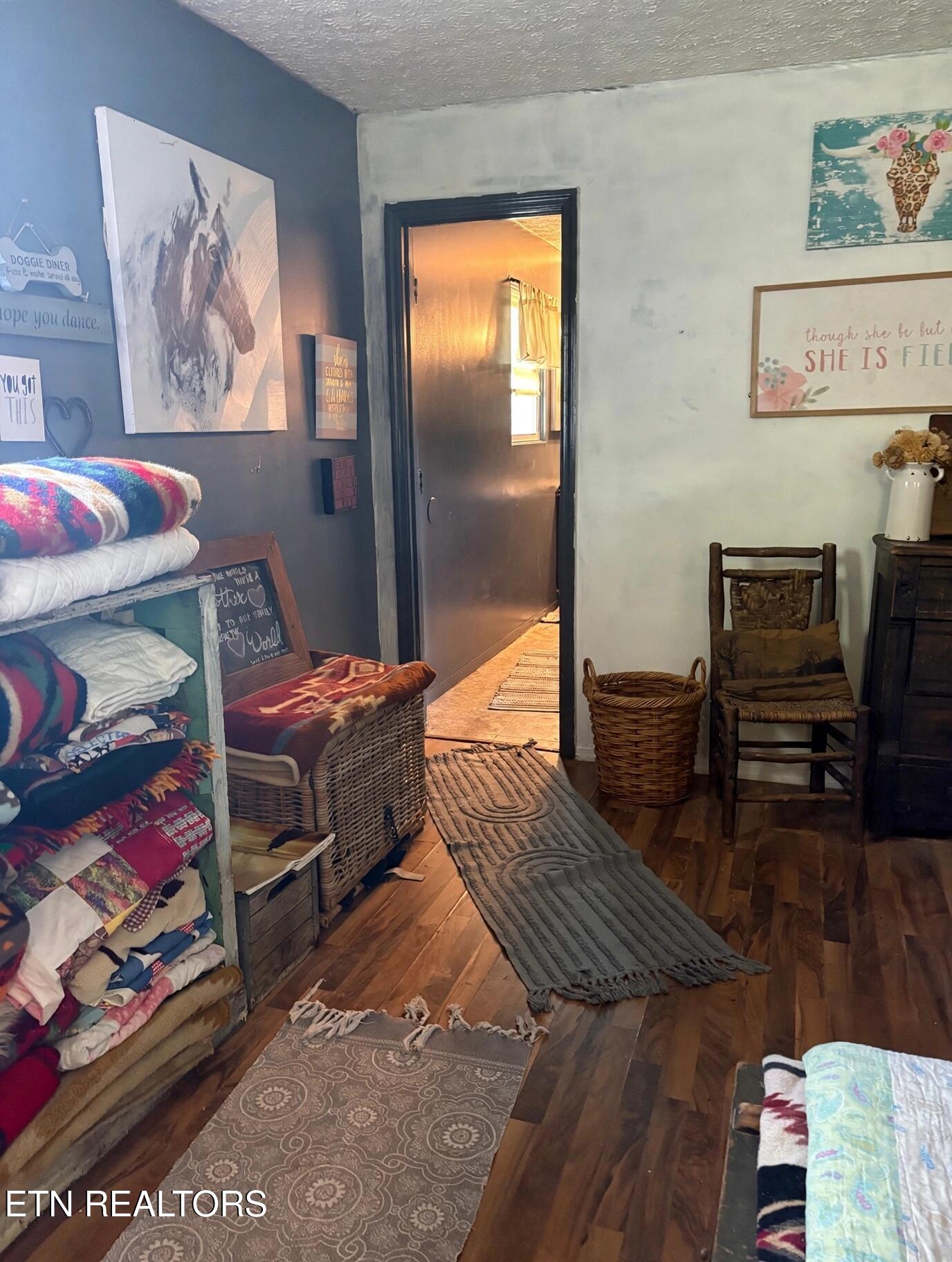 Furnished hallway with folded quilts, wicker baskets, wooden chairs, and patterned runners.