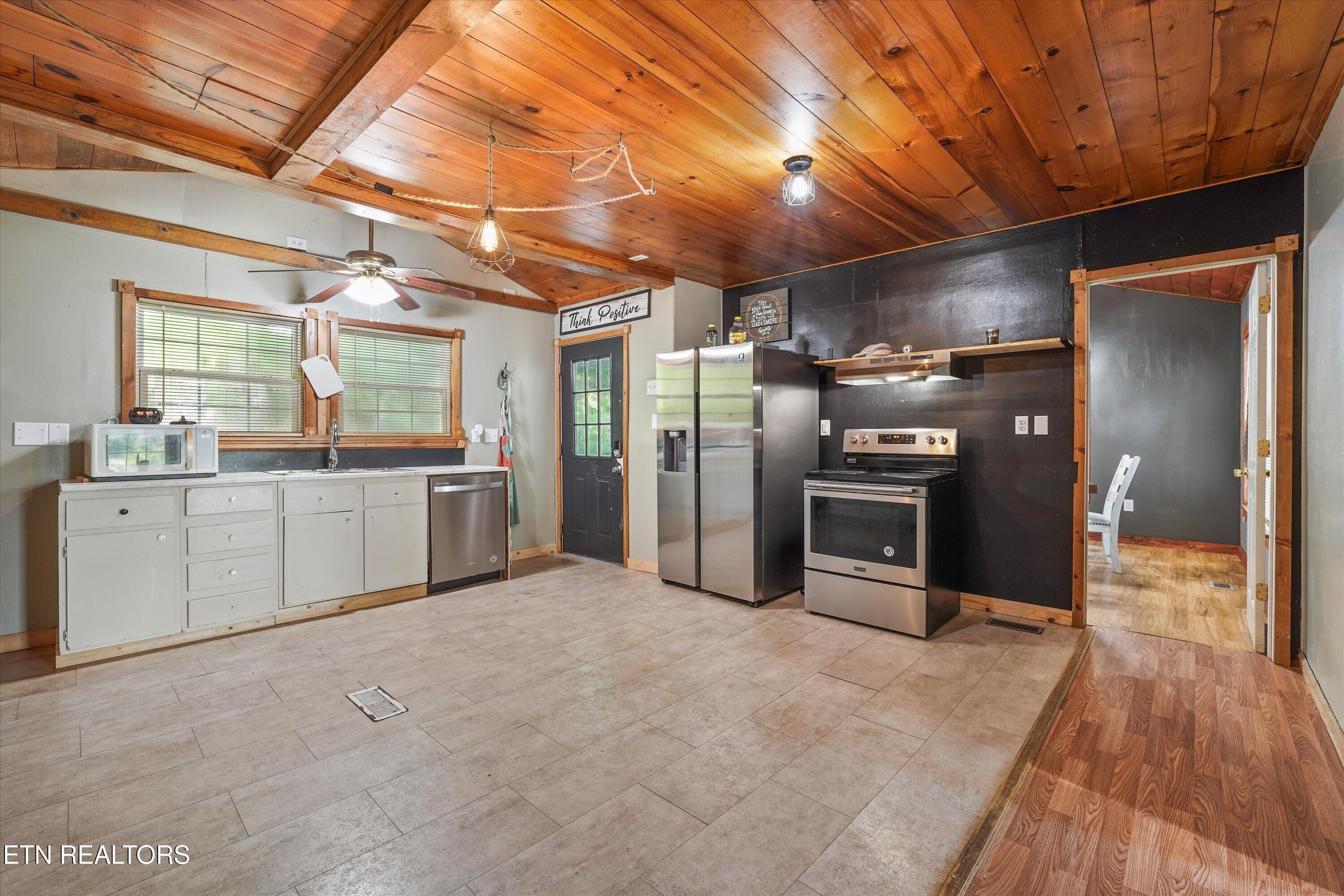 Kitchen with stainless steel appliances, white cabinets, and a distinctive wood-plank ceiling.