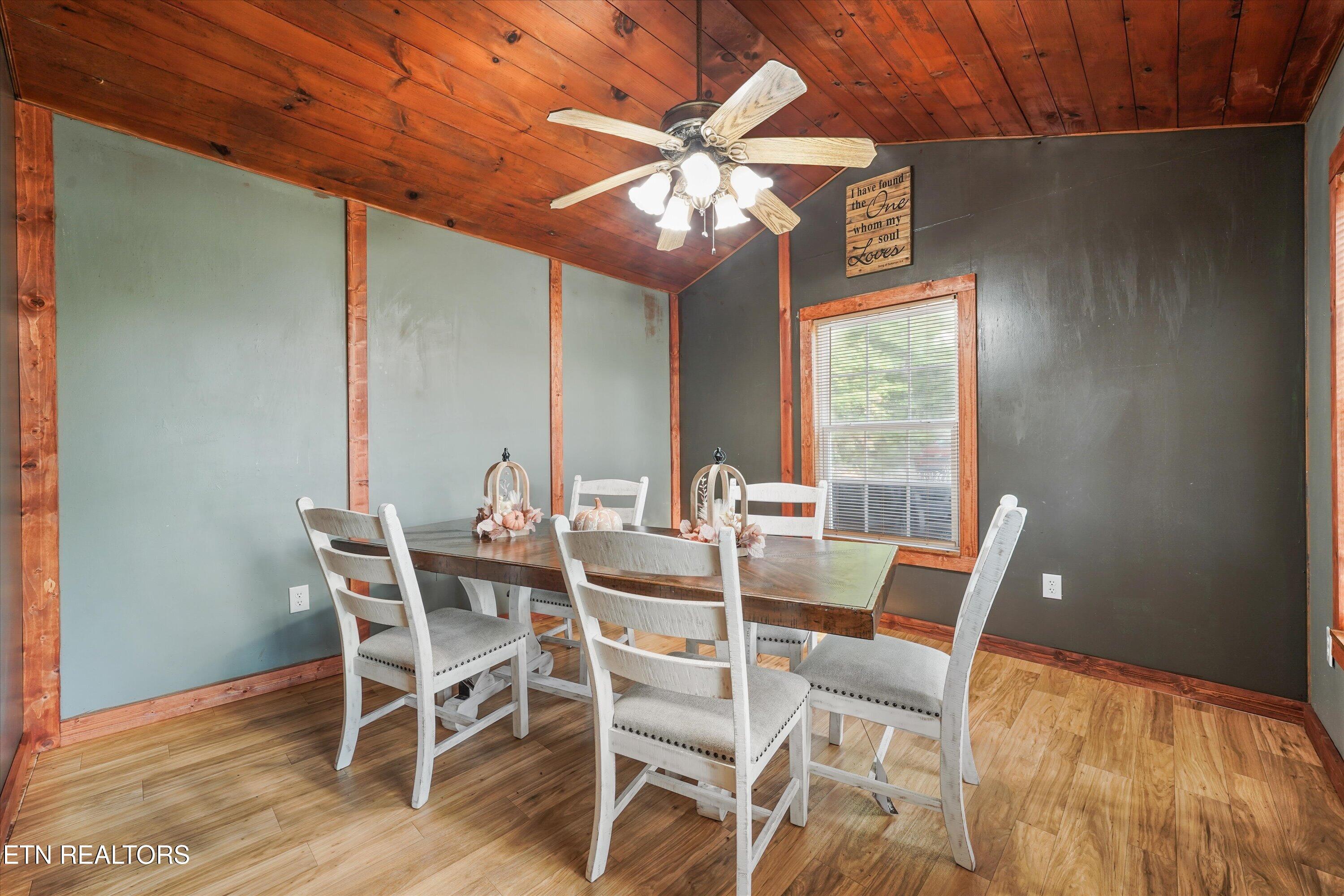 Dining room with white chairs, a wood table, and a vaulted wood ceiling with a ceiling fan.