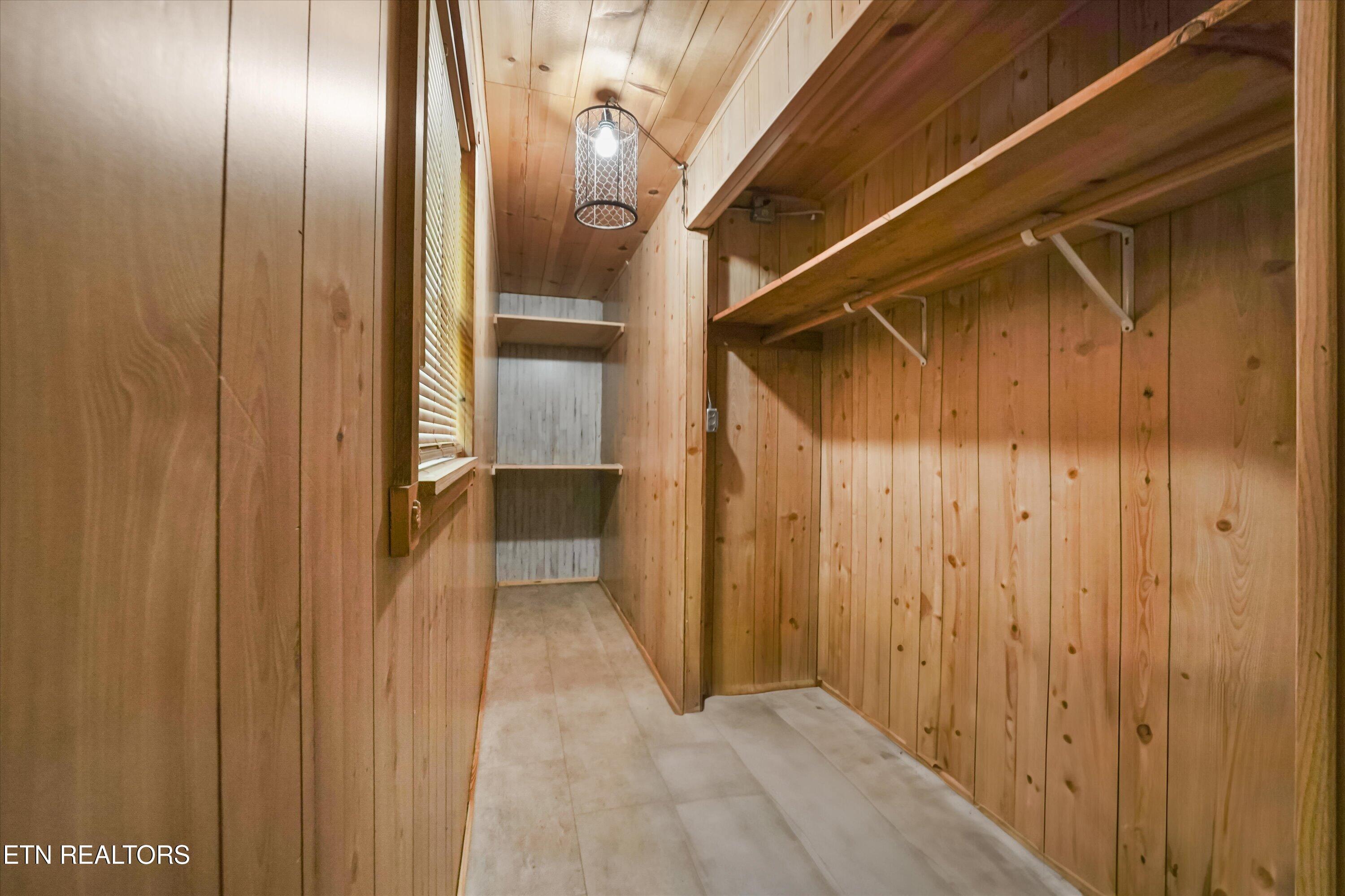 Wood-paneled walk-in closet with long hanging rods and built-in shelves.