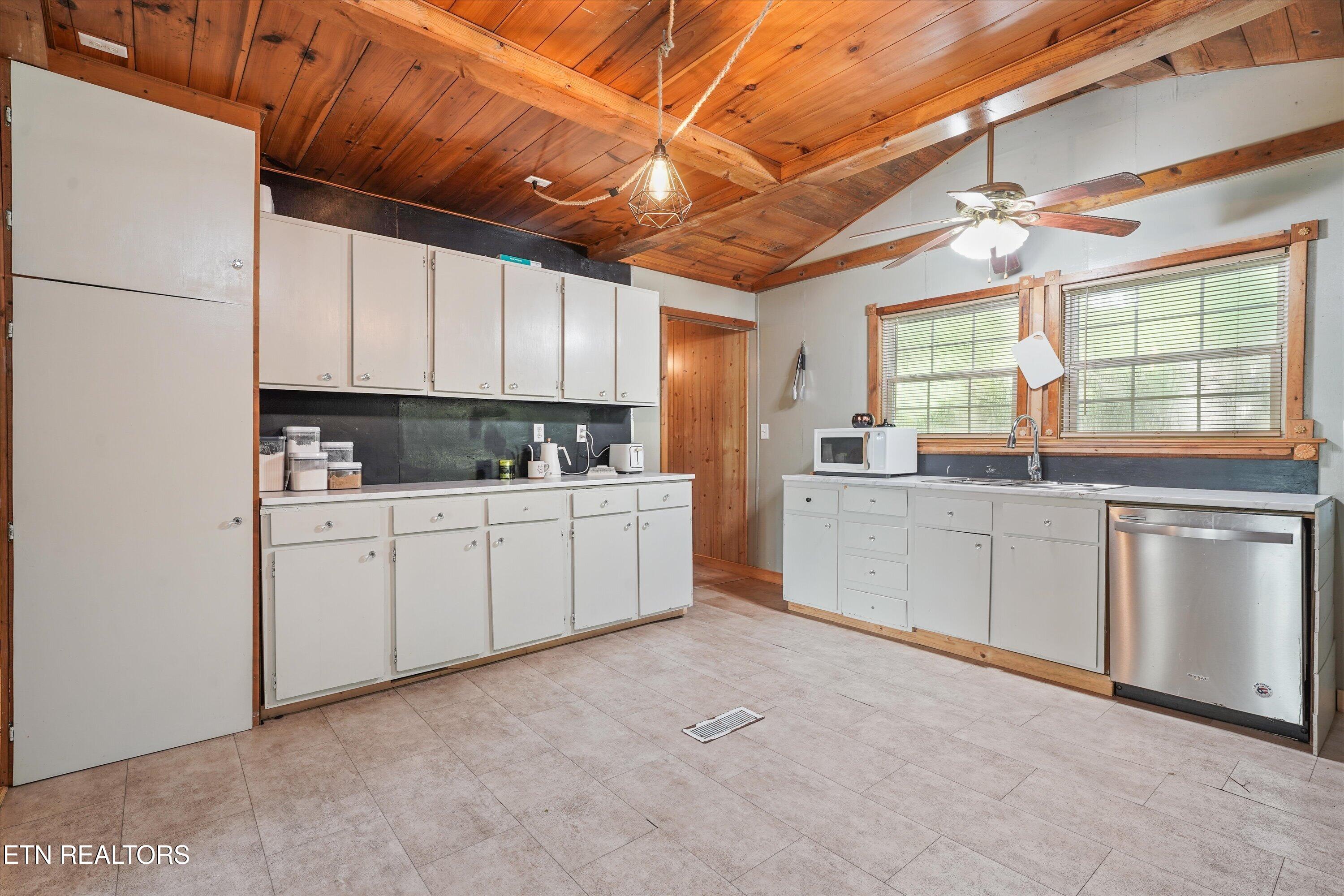 Kitchen with white cabinets, a double window over the sink, and a wood-plank ceiling.