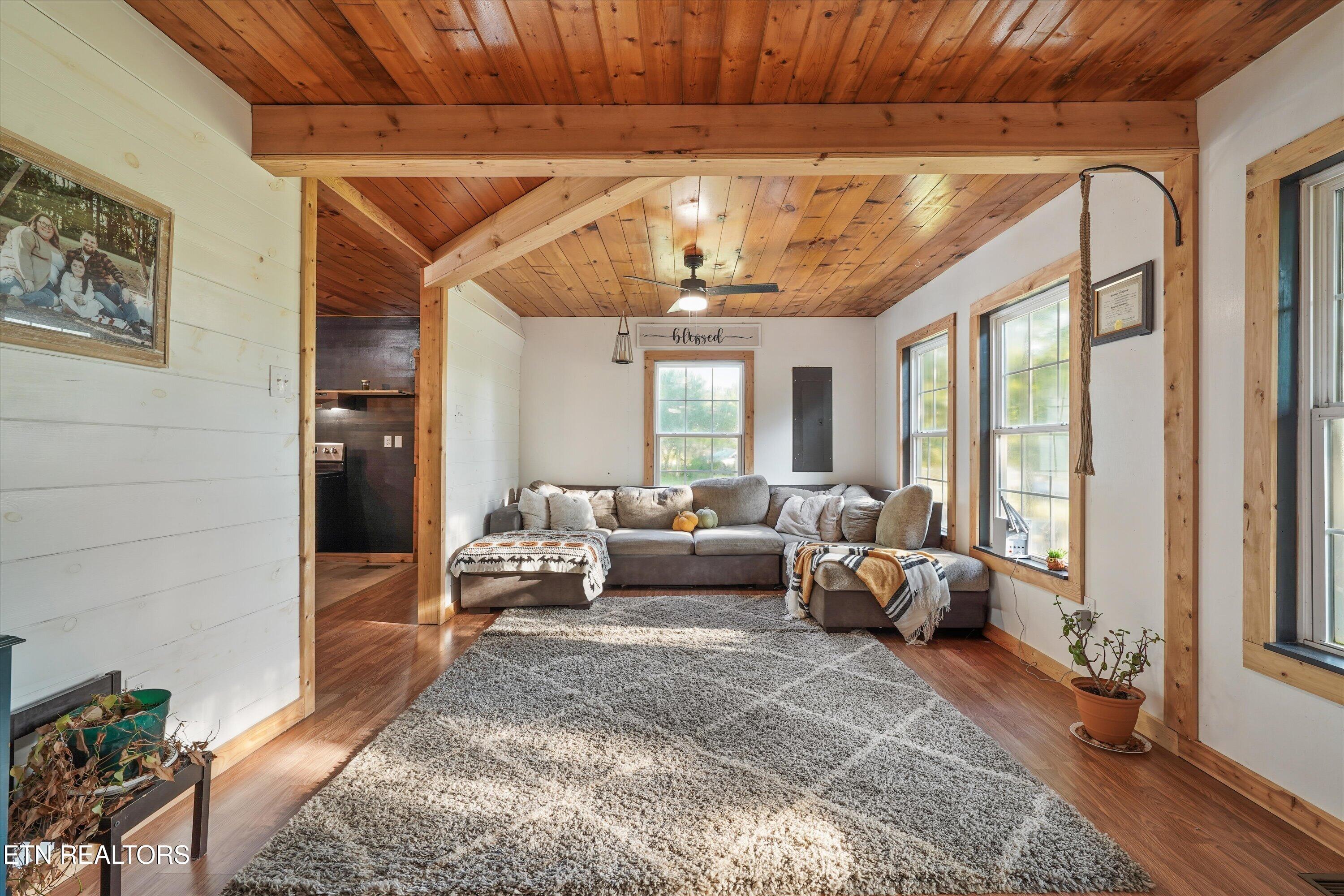 Living room with a gray sectional beneath a vaulted wood ceiling and exposed beams.