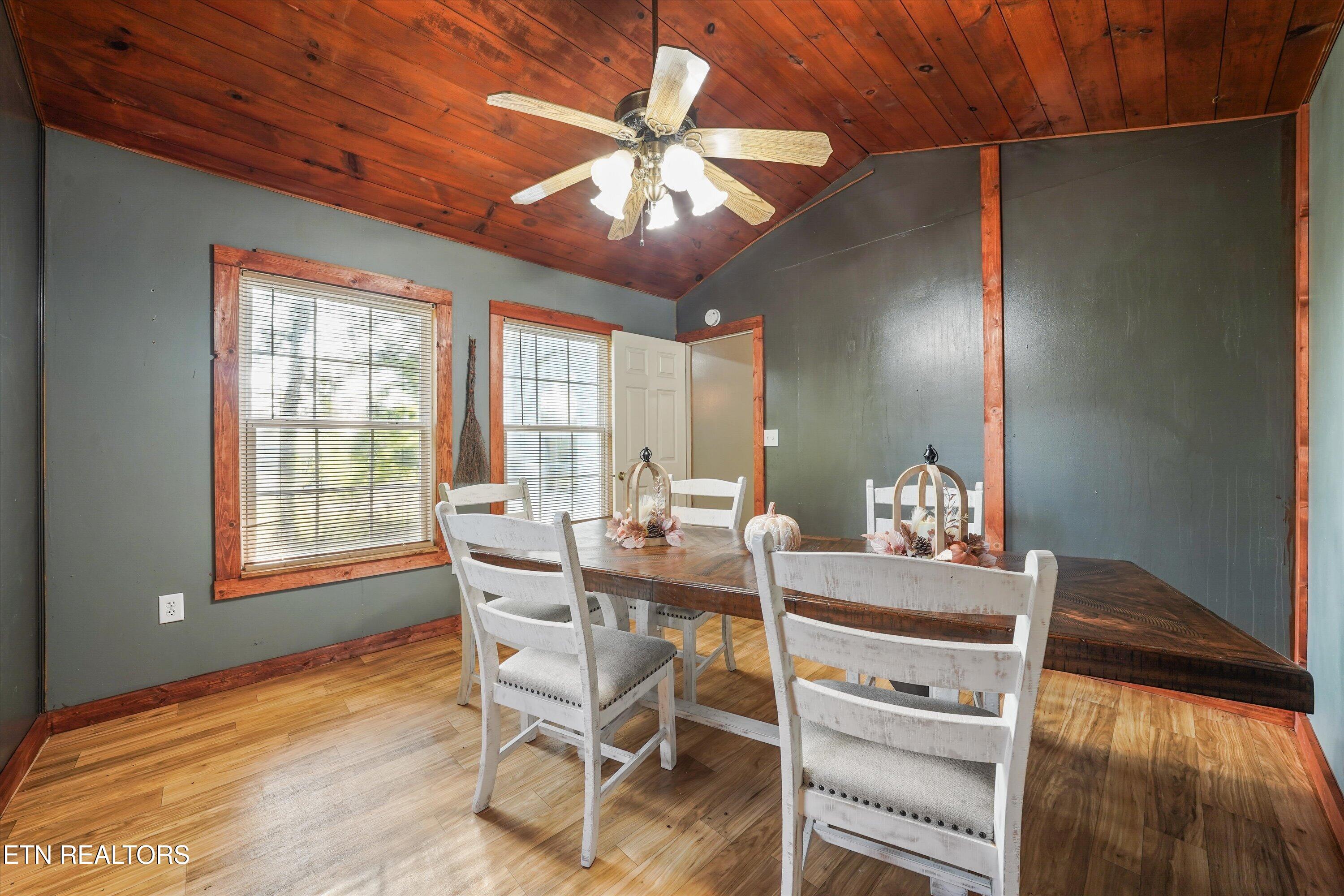 Dining room with a wood-plank ceiling, white chairs, and a long built-in bench.