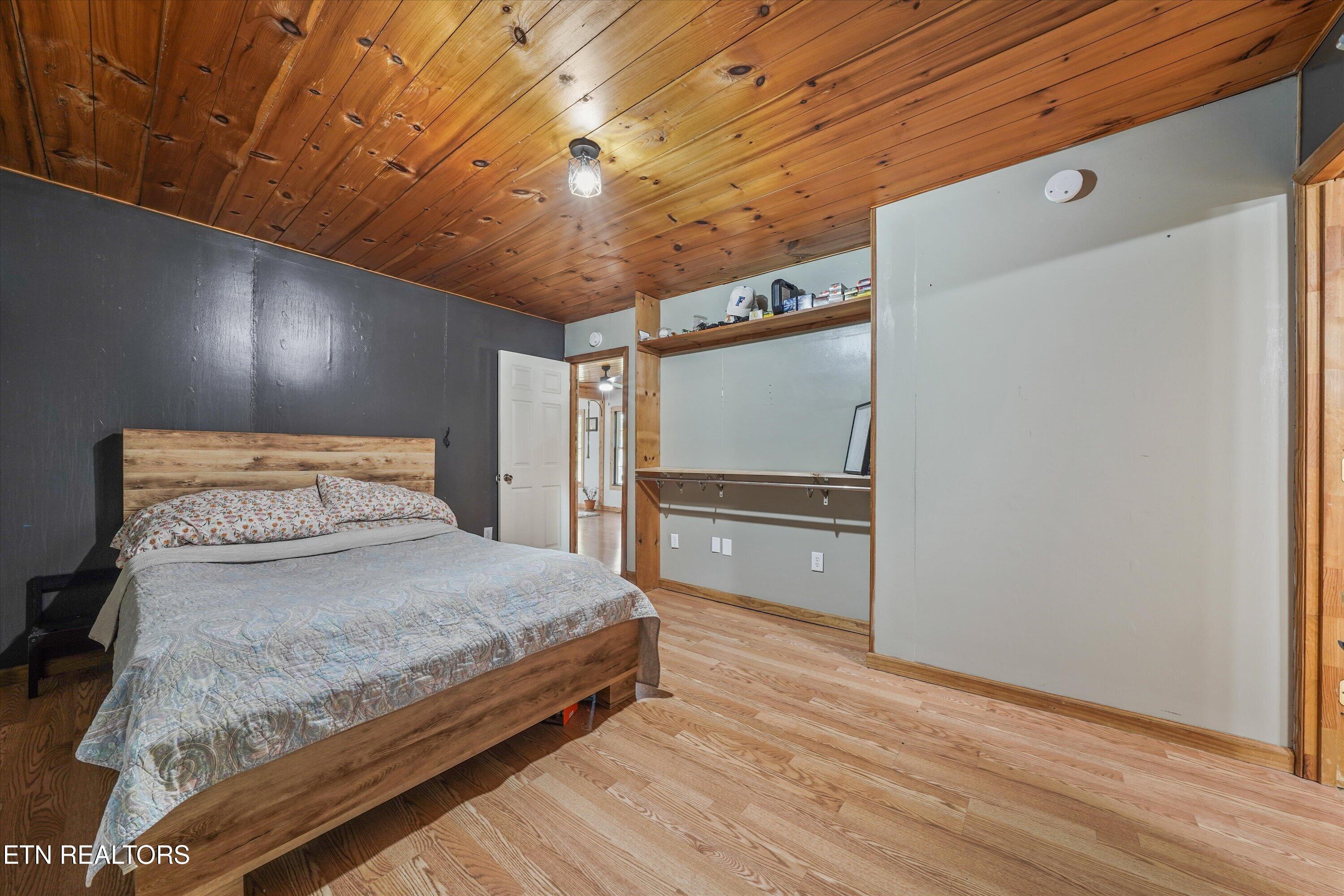 Bedroom with a wooden bed, knotty wood ceiling, and built-in open shelving.
