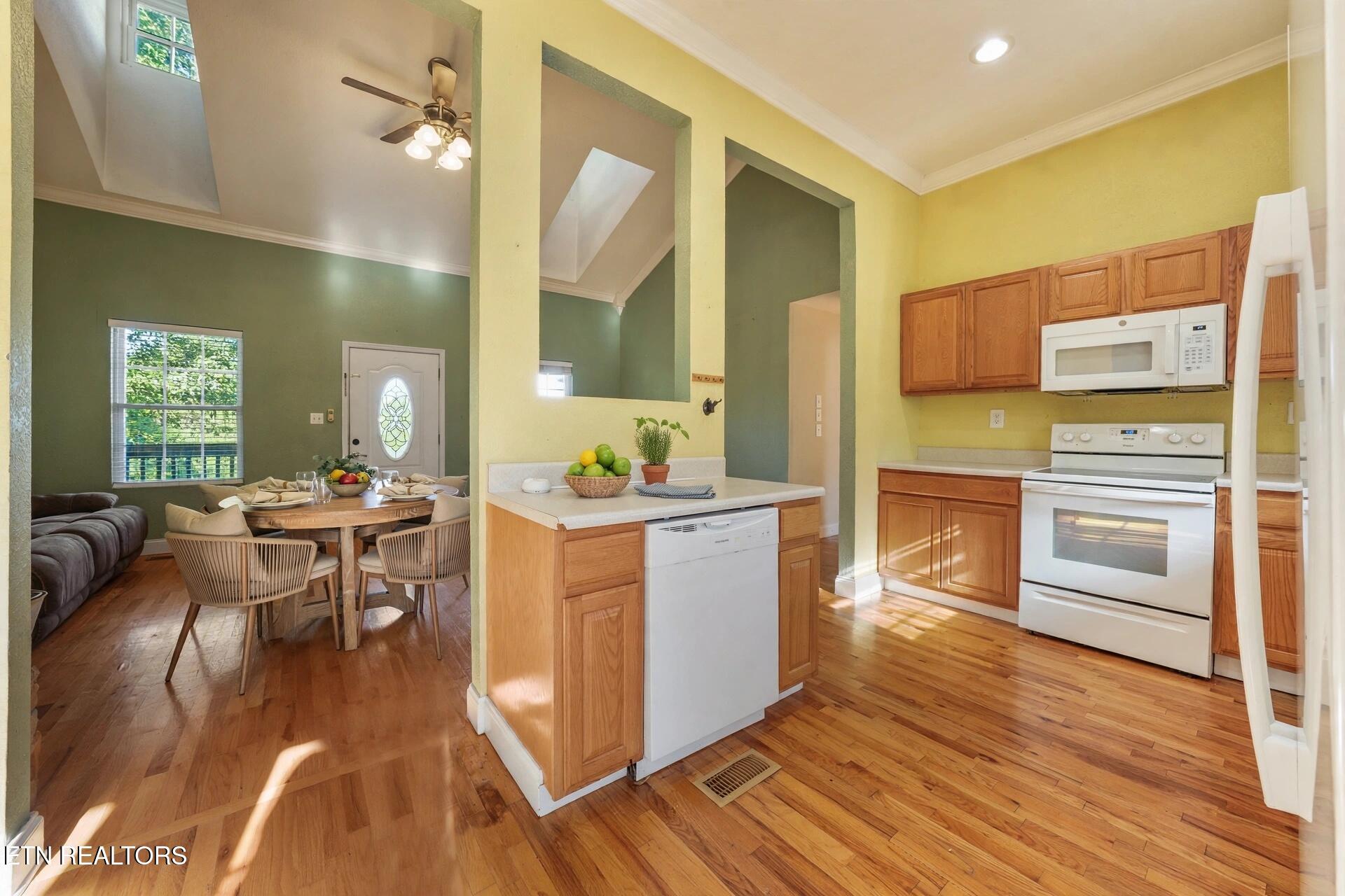 Open kitchen and dining area with wood cabinets, hardwood floors, and a central island.
