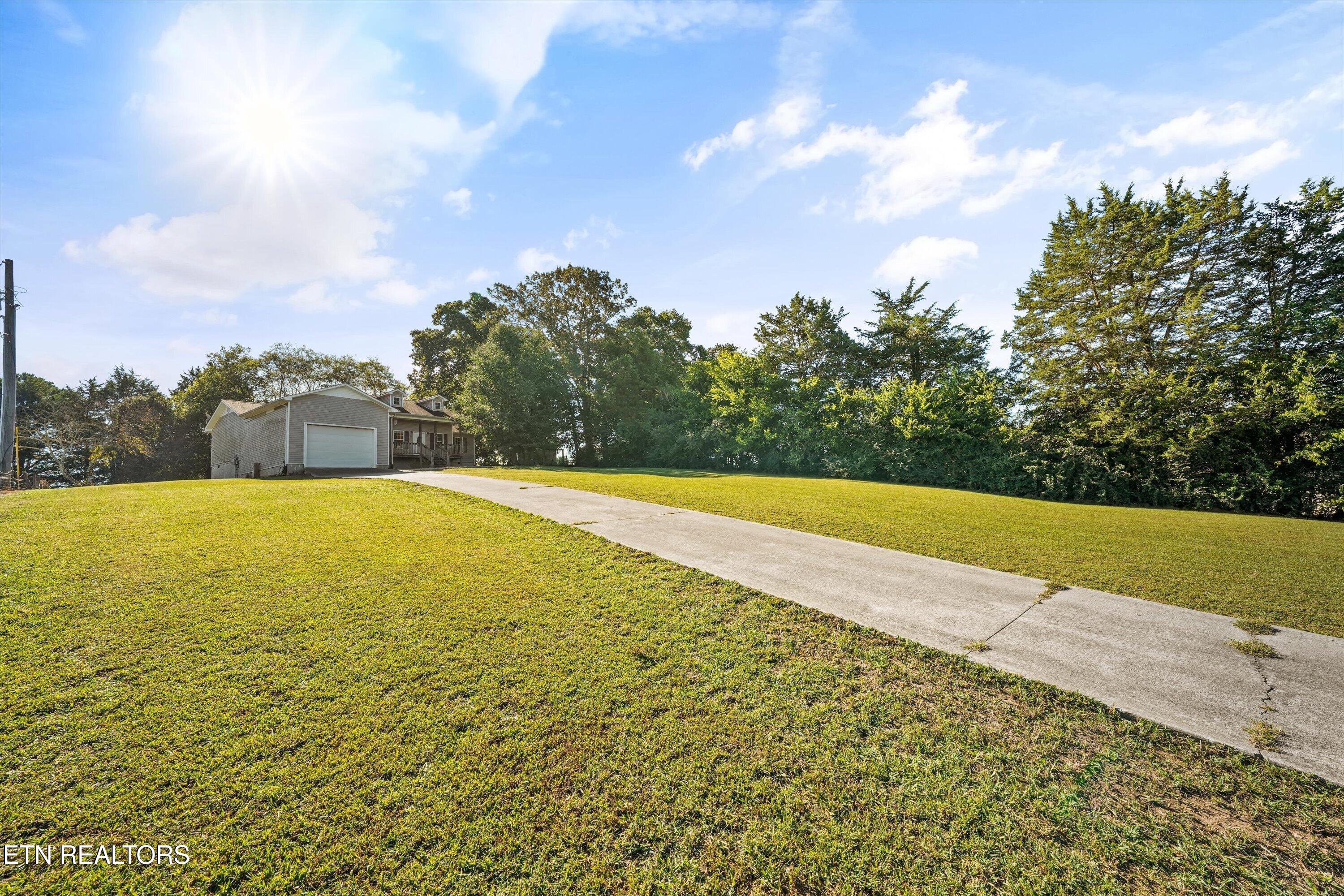 Gray-sided home with an attached garage, long concrete driveway, and broad lawn.