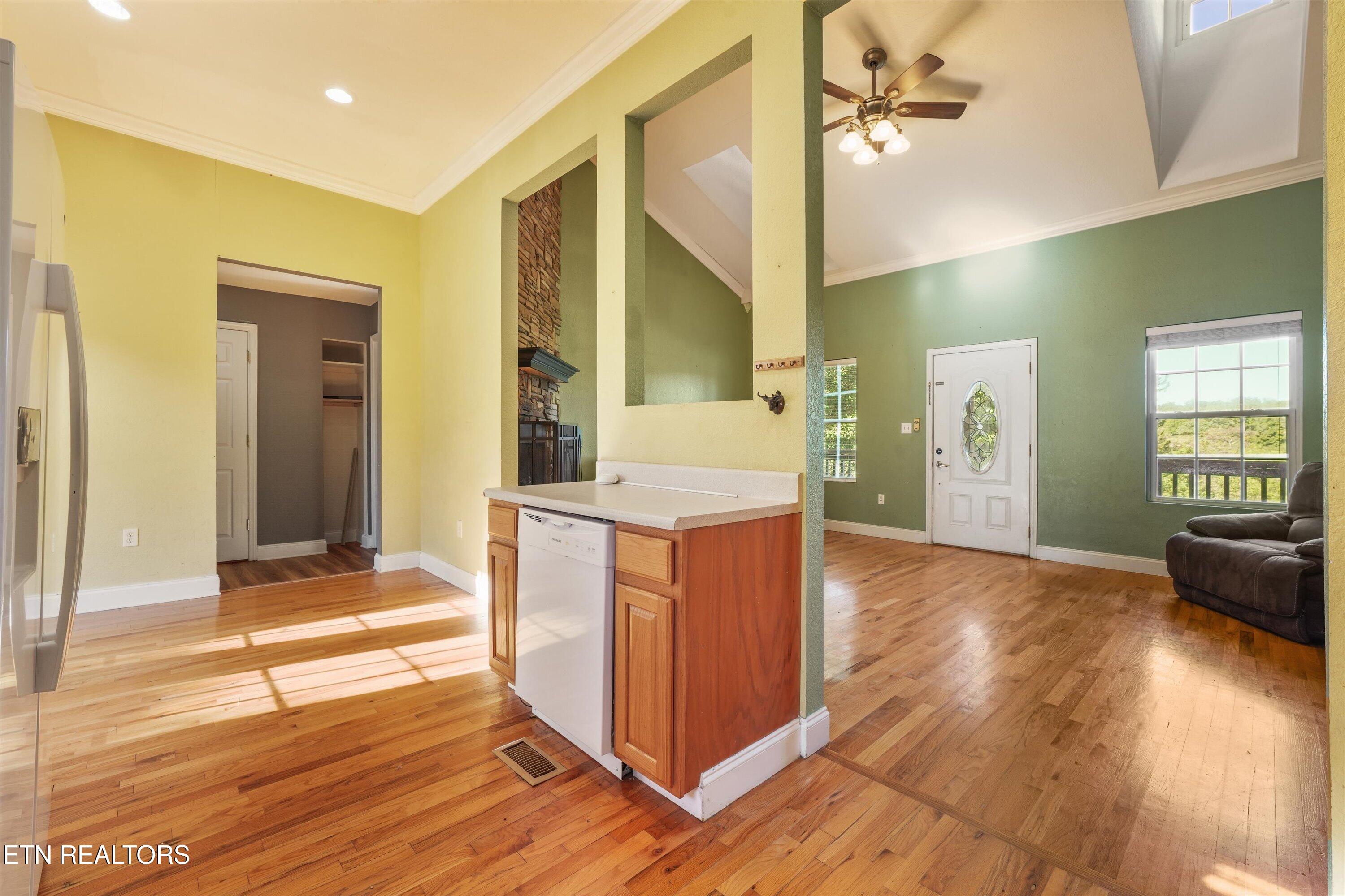 Open-plan kitchen and living room with hardwood floors, a wood peninsula, stone fireplace, and vaulted ceiling.