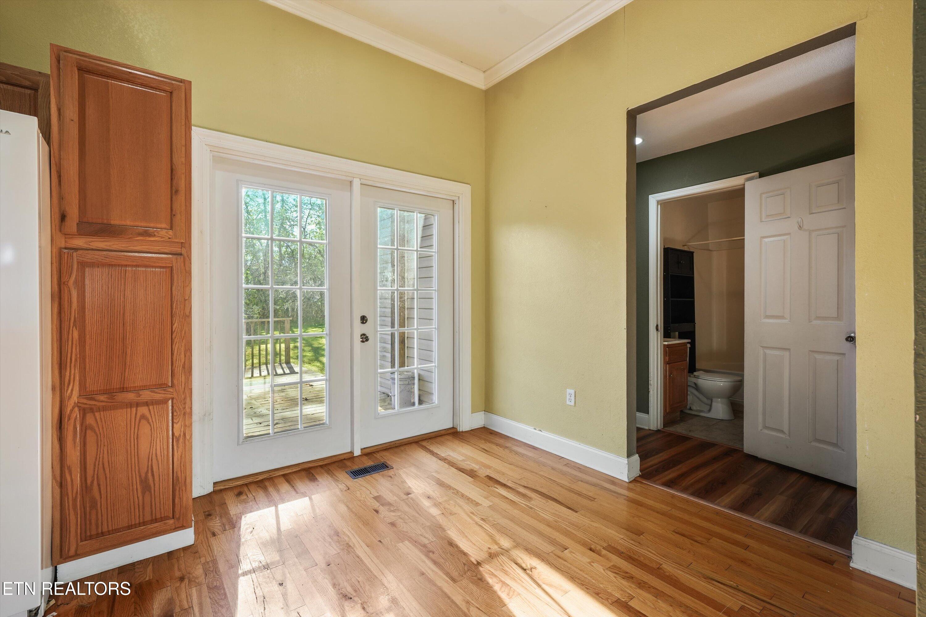 Kitchen with hardwood floors, wood cabinetry, and glass-paneled doors opening to a deck.
