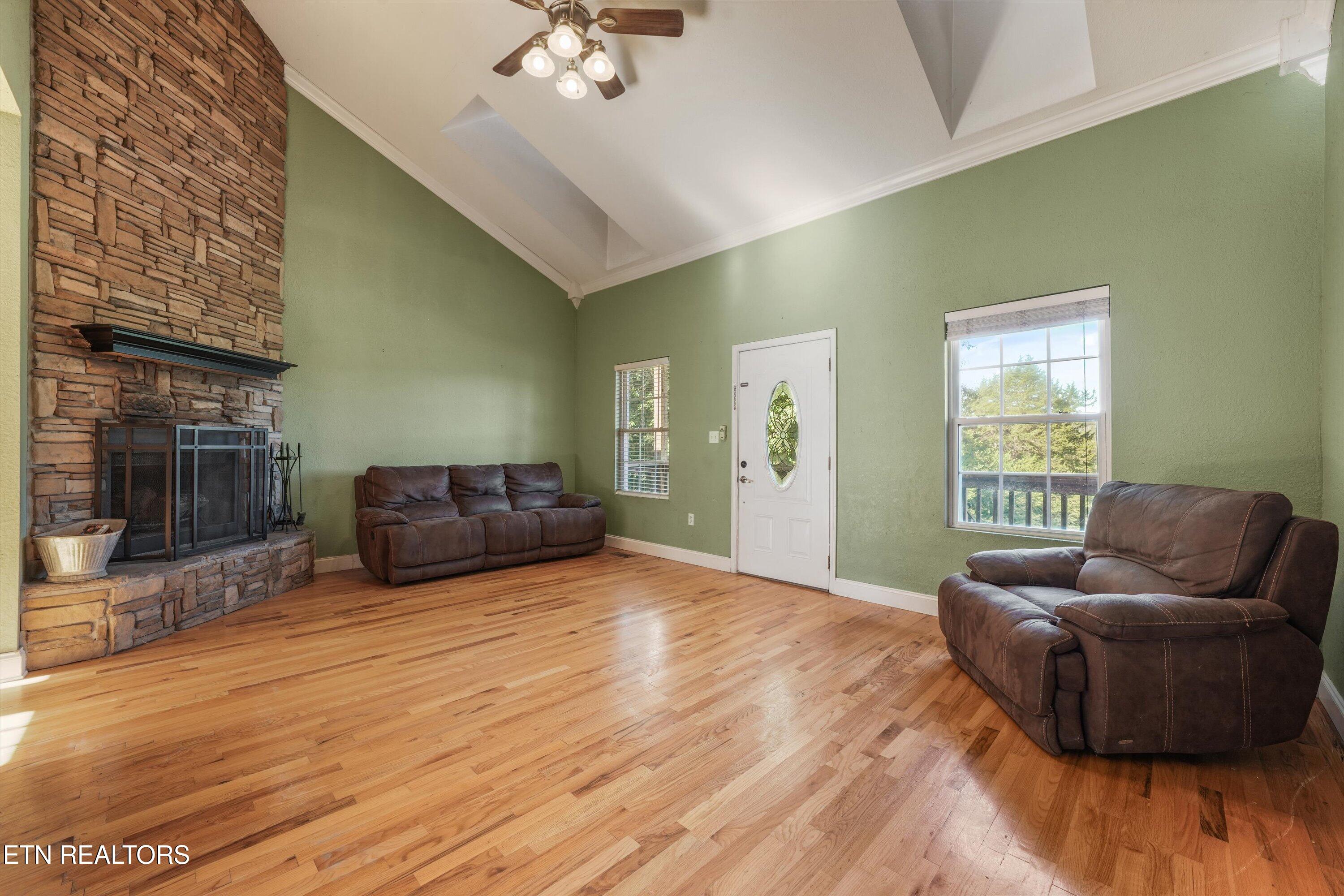 Living room with a stone fireplace, hardwood floors, and brown leather sofas.