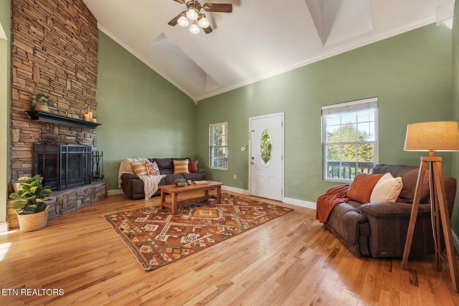 Living room with a tall stone fireplace, vaulted ceiling, green walls, and leather sofas.