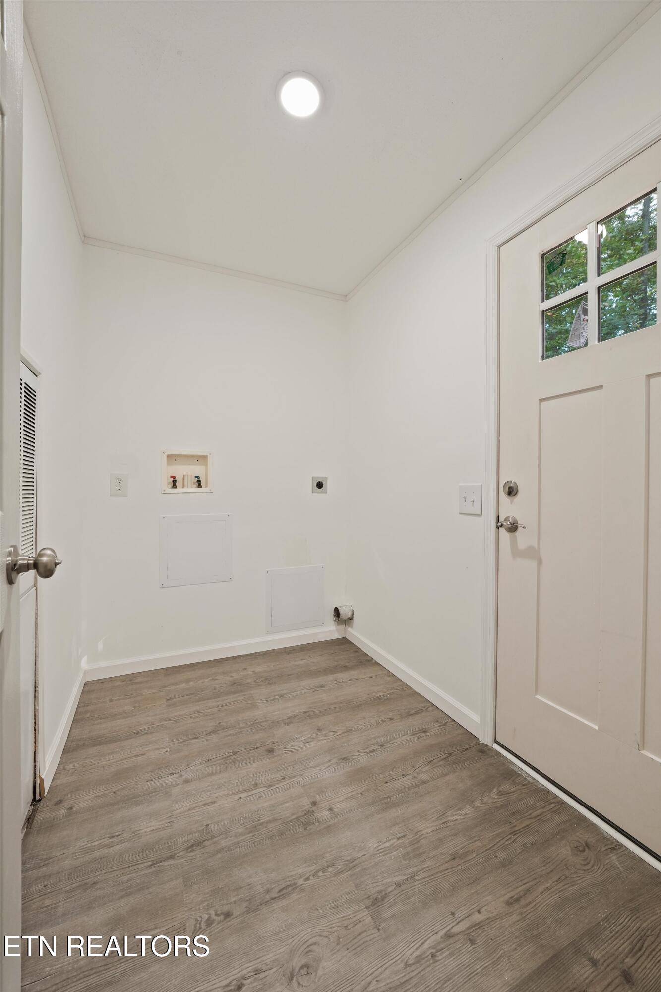 Vacant laundry room with washer hookups, wood-look flooring, and a door with upper windows.