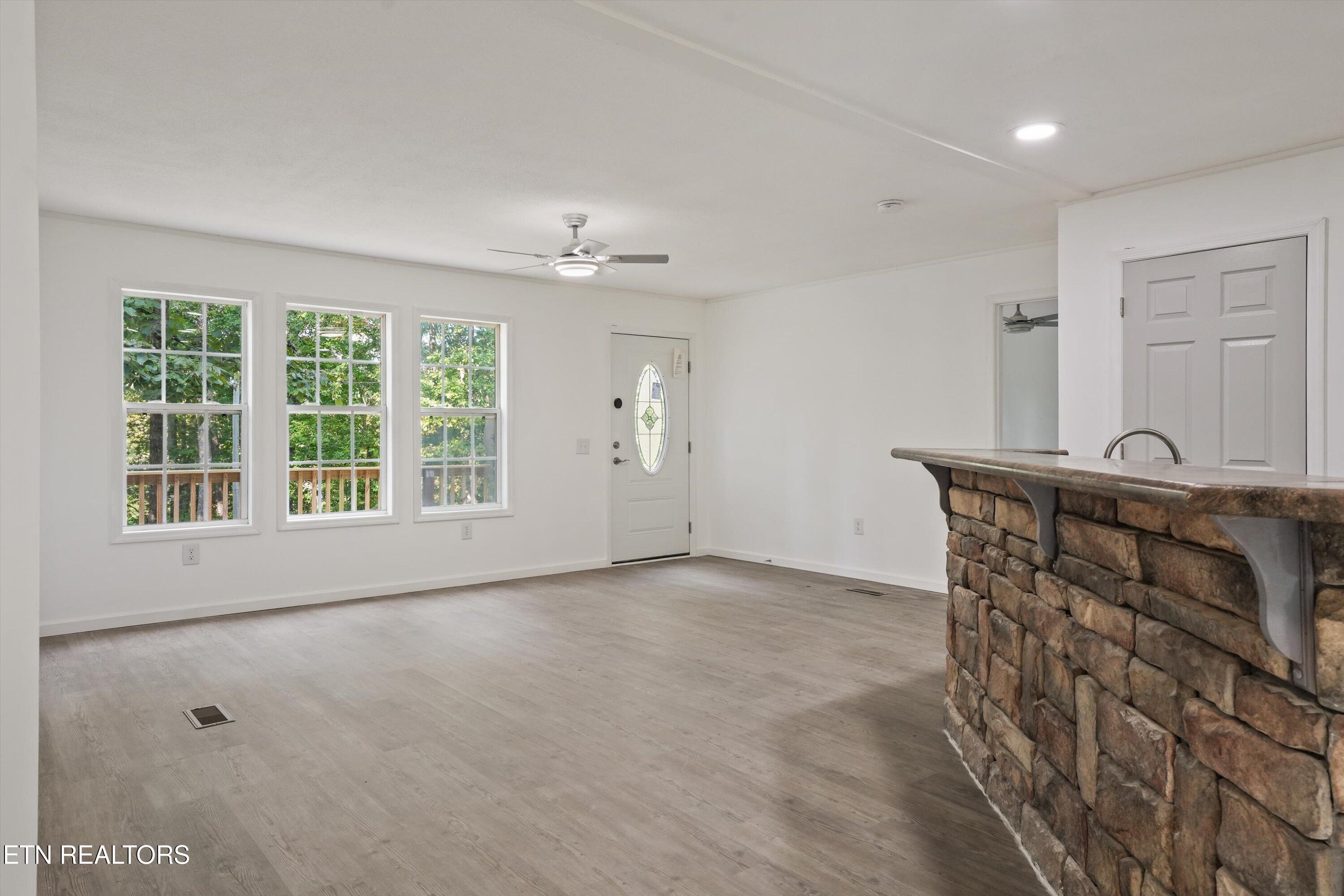 Unfurnished open room with a stone-front kitchen counter, three windows, and a glass-panel entry door.