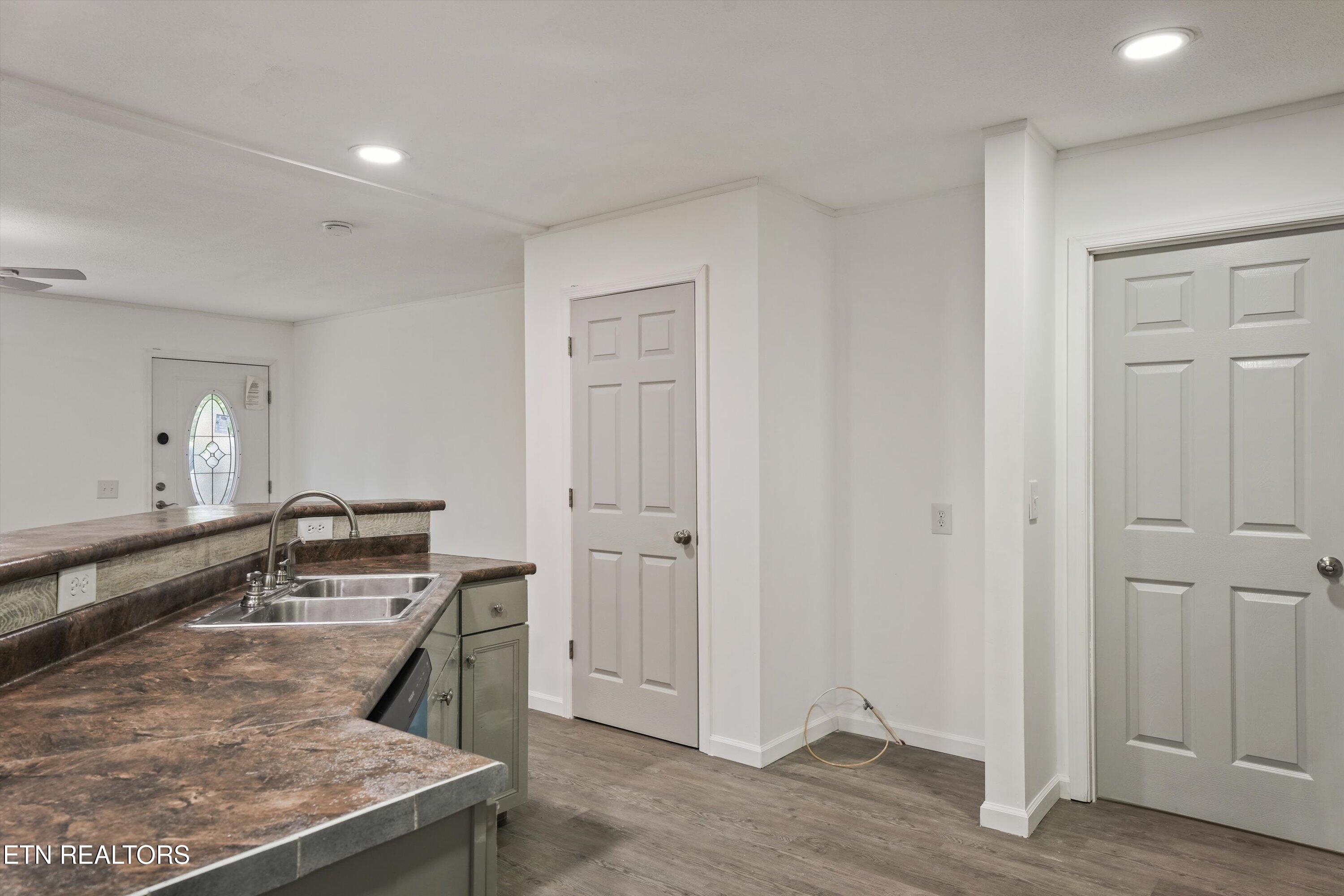 Kitchen and entry with a double-basin sink, brown countertops, gray cabinets, and paneled doors.