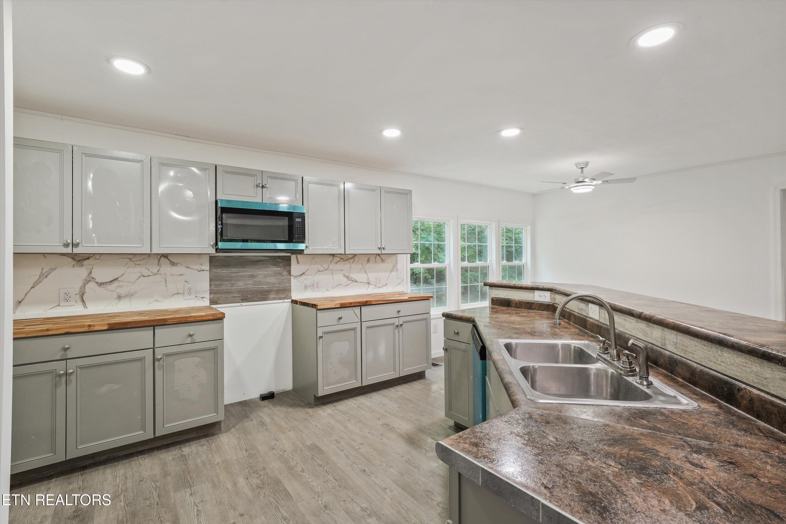 Kitchen with gray cabinets, butcher-block counters, and a large island with a double sink.