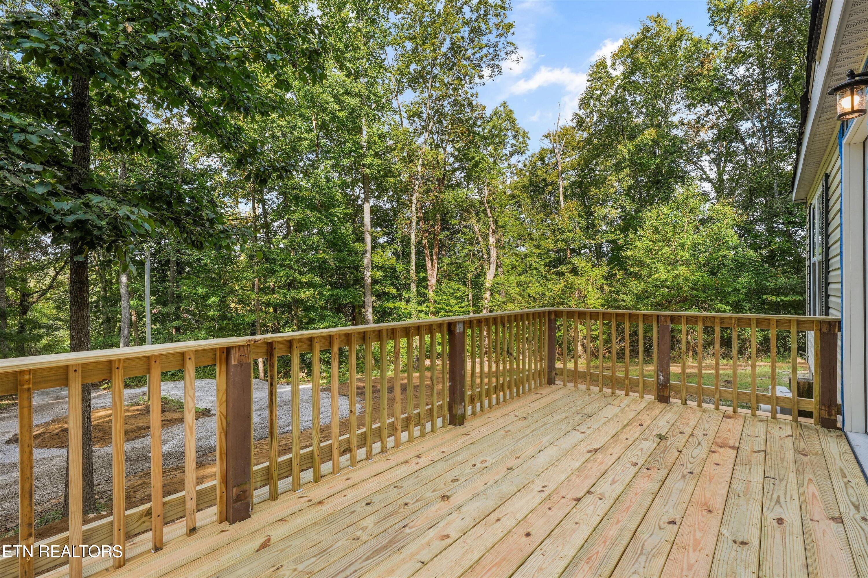 Wooden deck with fresh plank flooring and railings overlooking a wooded yard.