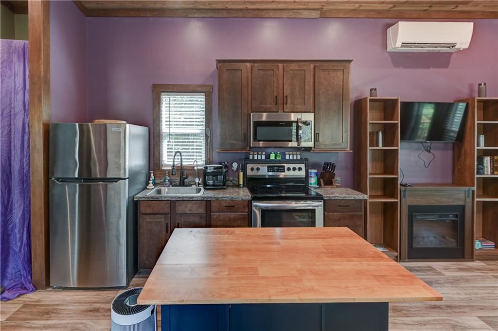 Kitchen with dark wood cabinets, stainless appliances, and a large wood-topped island.