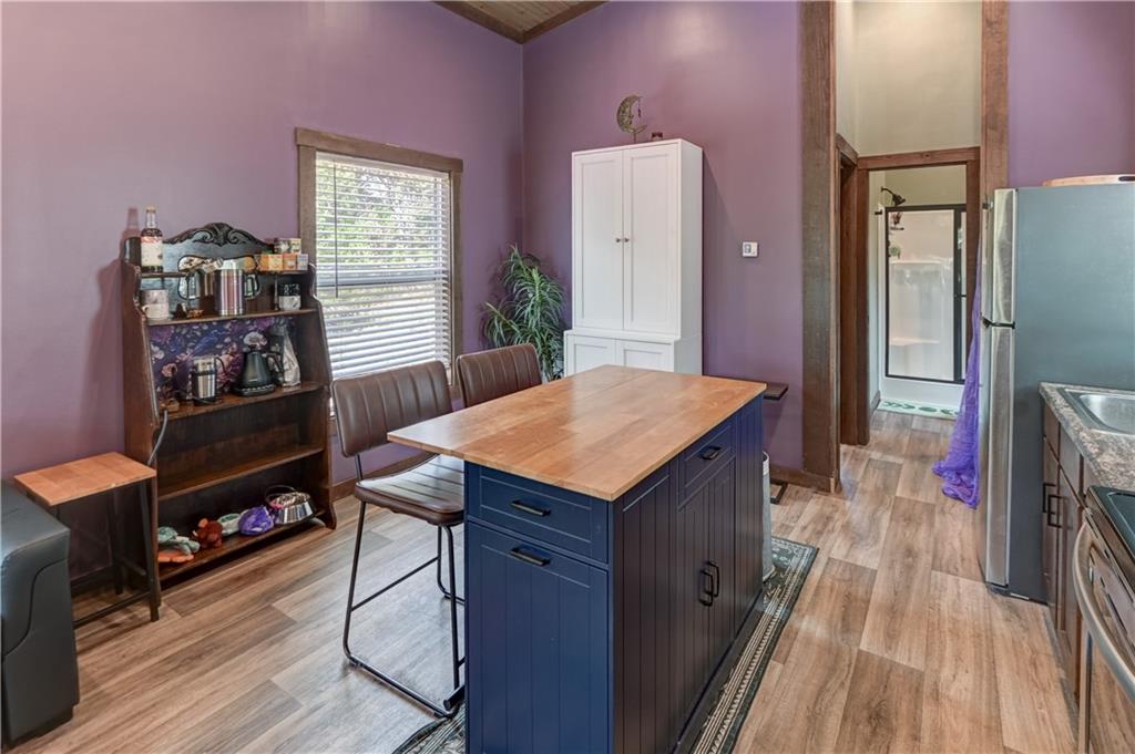 Kitchen with a navy island and butcher-block top, purple walls, and a dining table by the window.