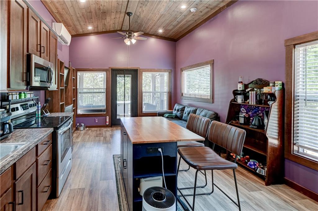 Kitchen and dining area with a central island, dark wood cabinetry, and a vaulted wood ceiling.
