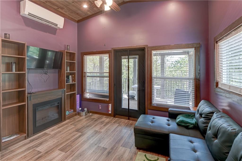 Living room with purple walls, a black sectional sofa, and an electric fireplace beside a glass door to the deck.
