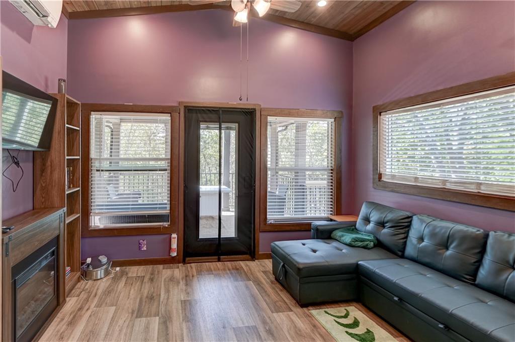 Living room with purple walls, vaulted wood ceiling, and dark leather sectional sofa.