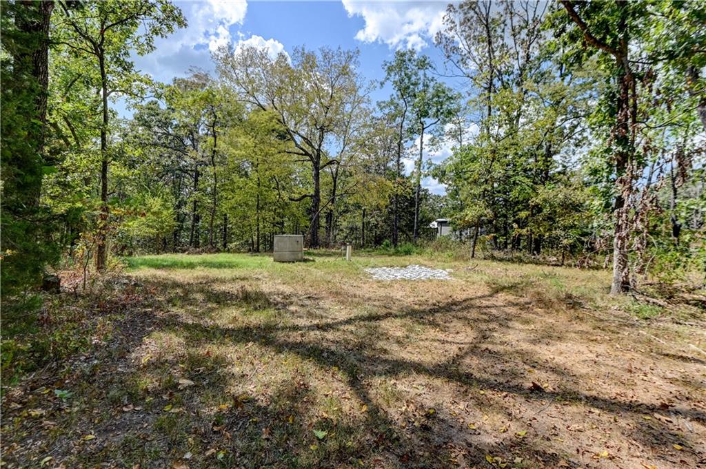 Wooded property clearing with a utility box and gravel patch.