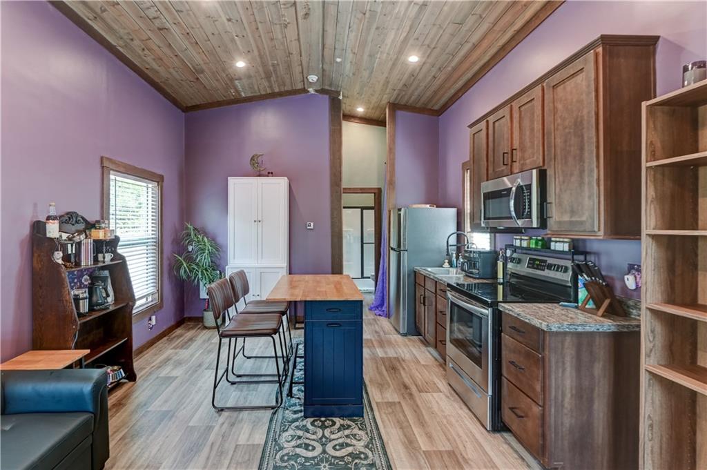 Kitchen with purple walls, a wood-plank ceiling, stainless steel appliances, and a blue island.