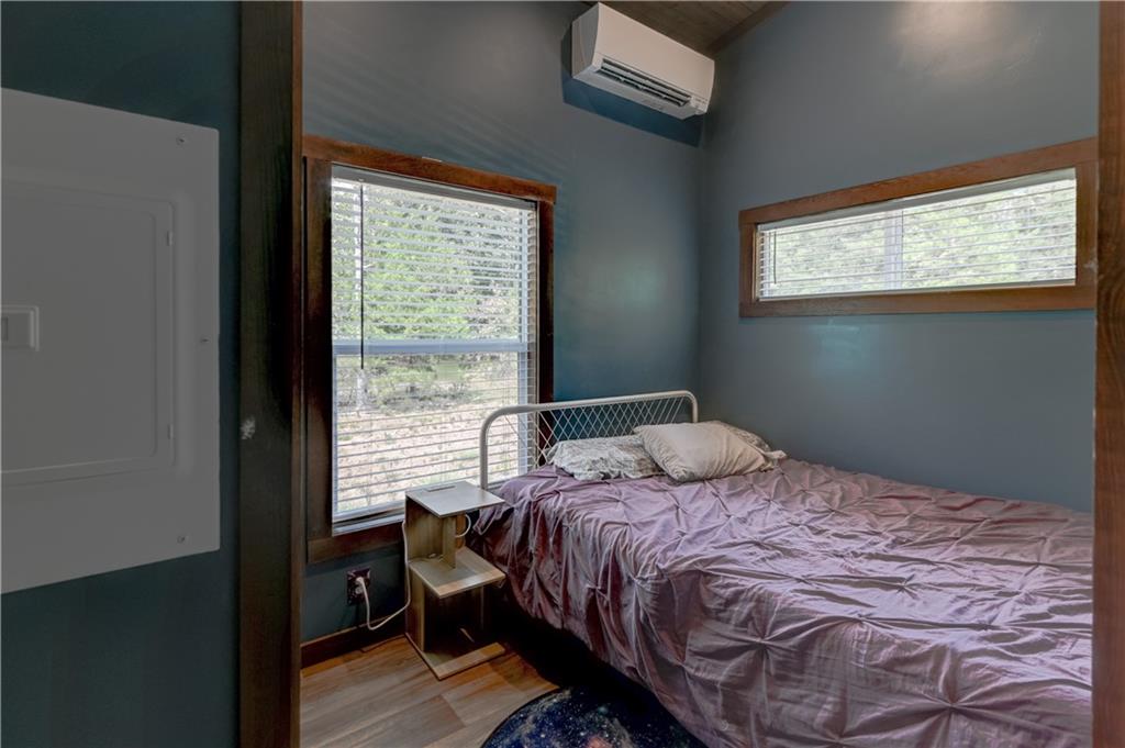 Bedroom with mauve bedding, dark teal walls, and two wood-trimmed windows.