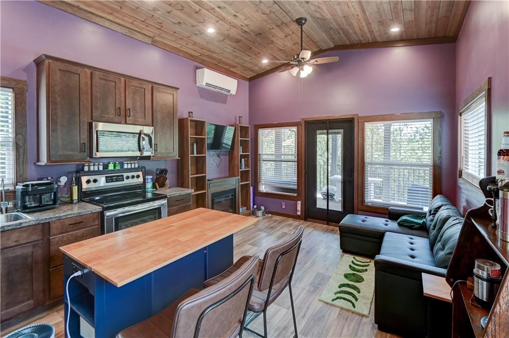 Kitchen and living area with a blue butcher-block island, purple walls, and a wood-plank ceiling.