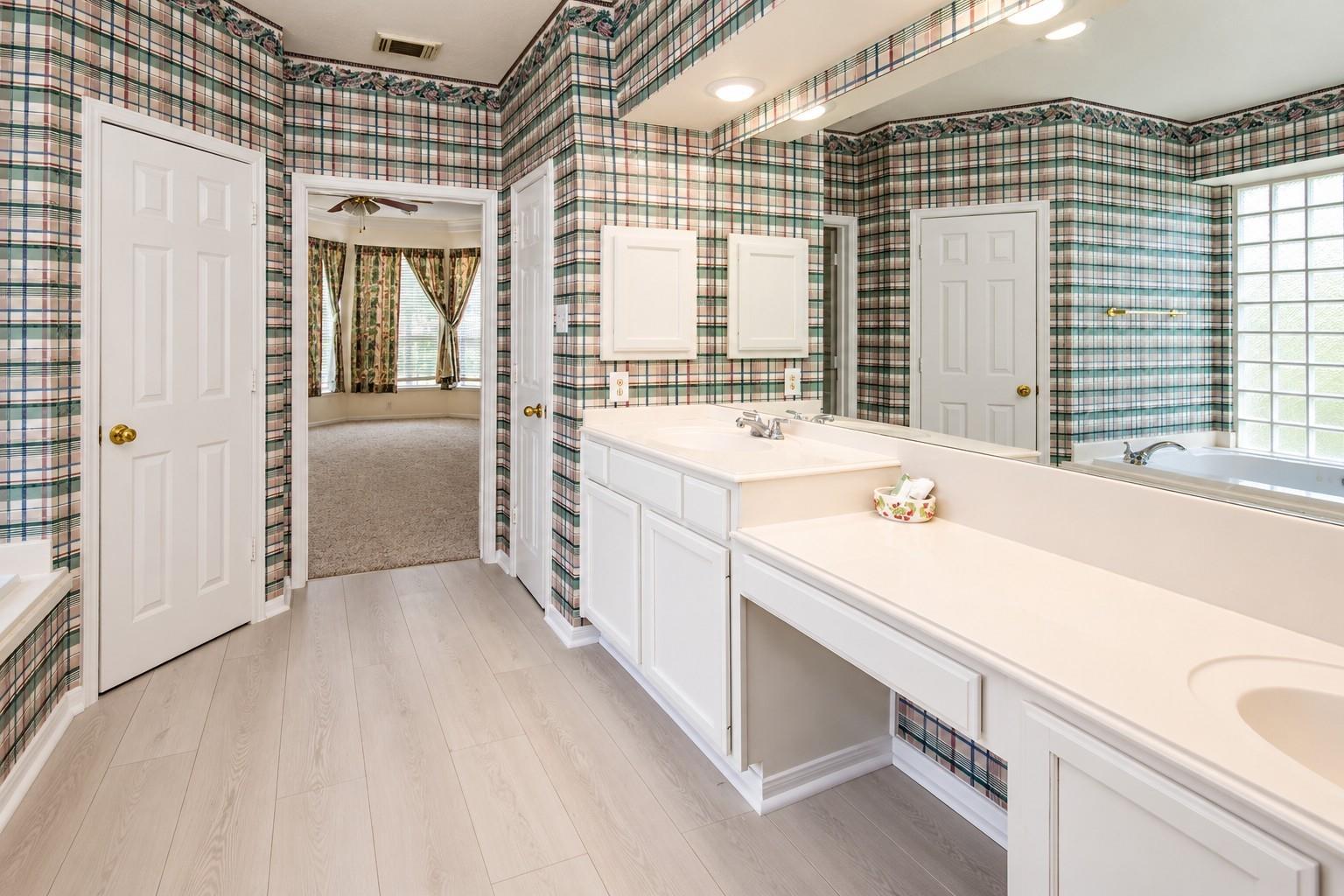 Bathroom with long white vanity, glass-block windows, and plaid wallpaper.