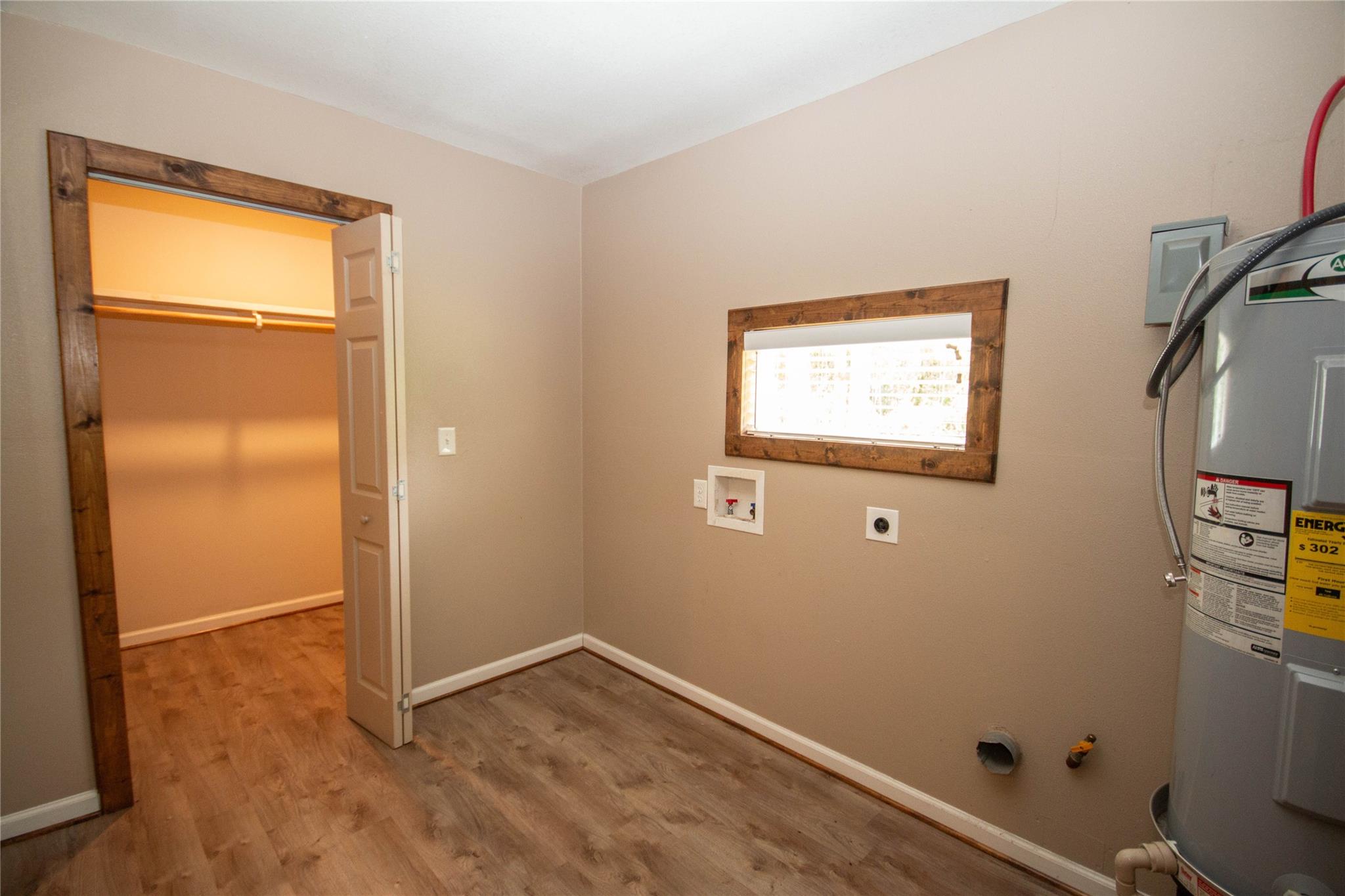 Laundry room with an open closet, washer hookups, and a water heater.