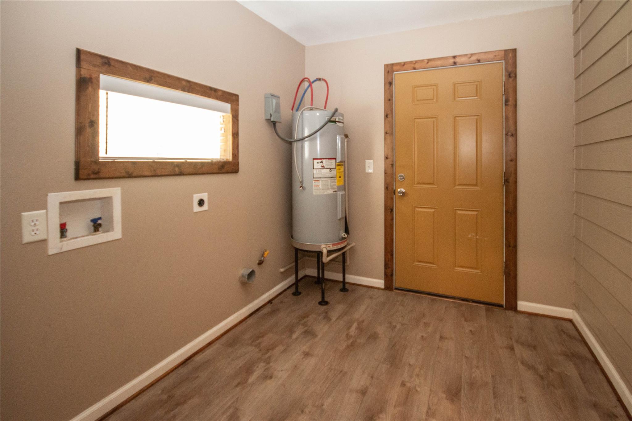Utility room with a tank water heater, washer hookups, and a mustard-yellow door.