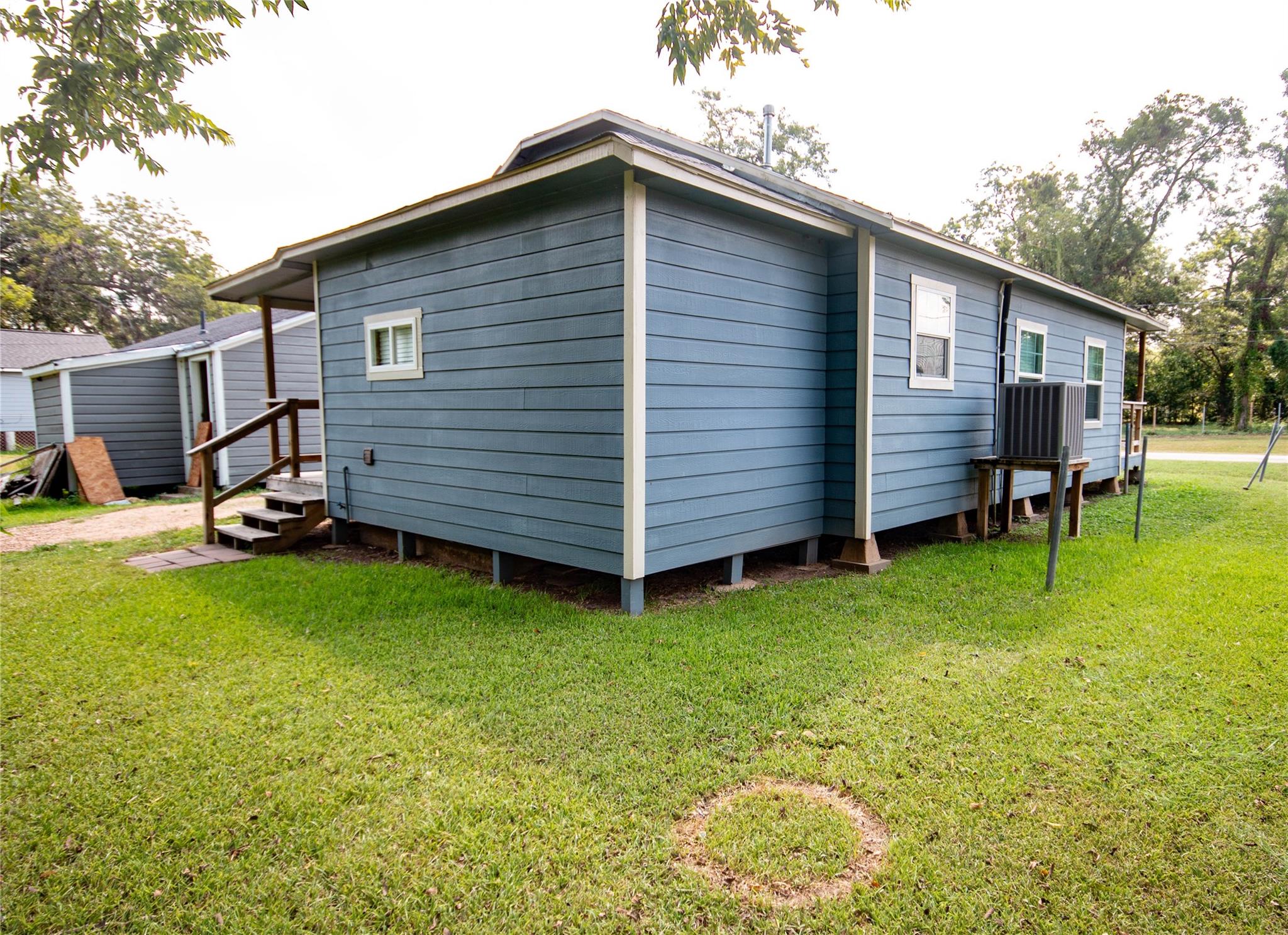 Blue house raised above a green lawn, with white trim and an exterior air-conditioning unit.