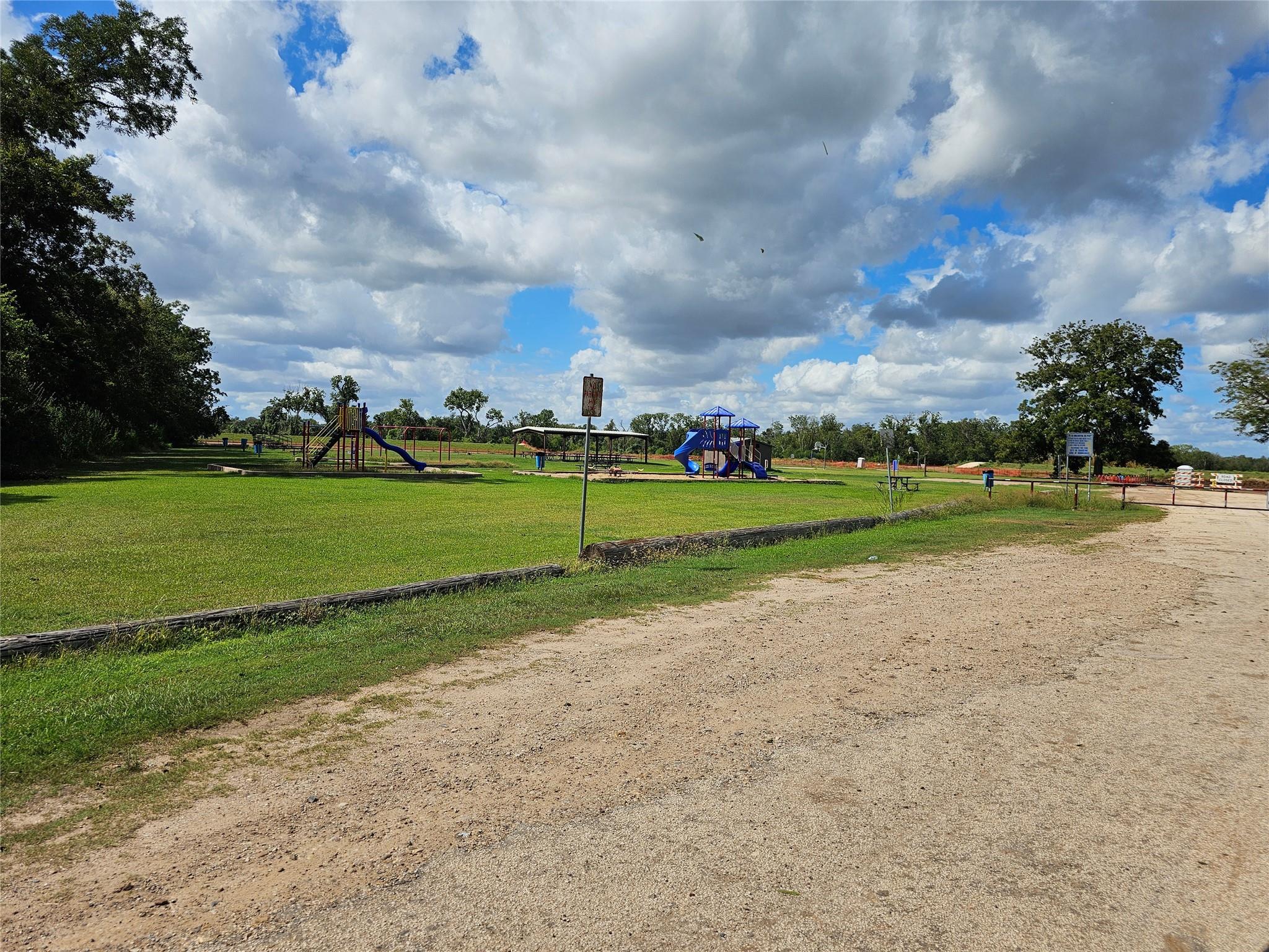 Park playground with colorful play structures and slides beside a gravel road.