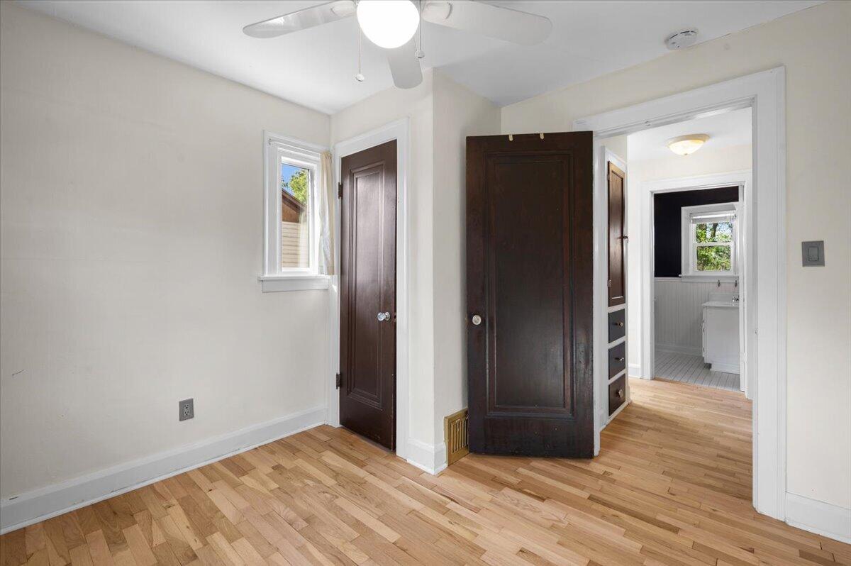 Unfurnished bedroom with hardwood floors, dark wood closet doors, and an adjoining bathroom.