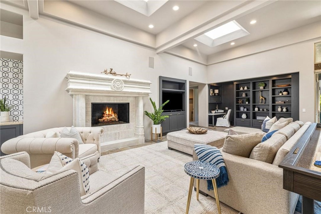 Living room with a marble fireplace, built-in shelves, and neutral seating.