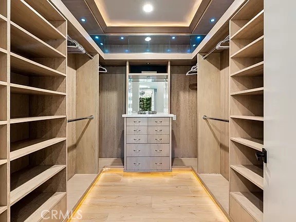 Walk-in closet with wood shelving on both sides and a central drawer island beneath a mirror.