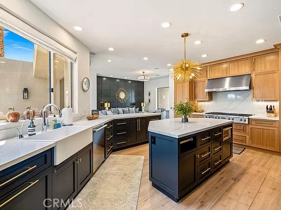 Open-plan kitchen with a dark island, warm wood cabinetry, and a gold starburst pendant light.