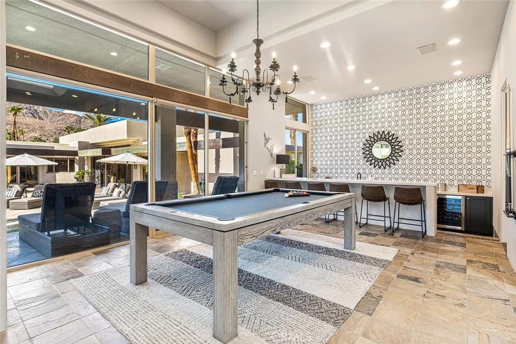 Game room with a pool table and bar, opening through large windows to a mountain-view patio.