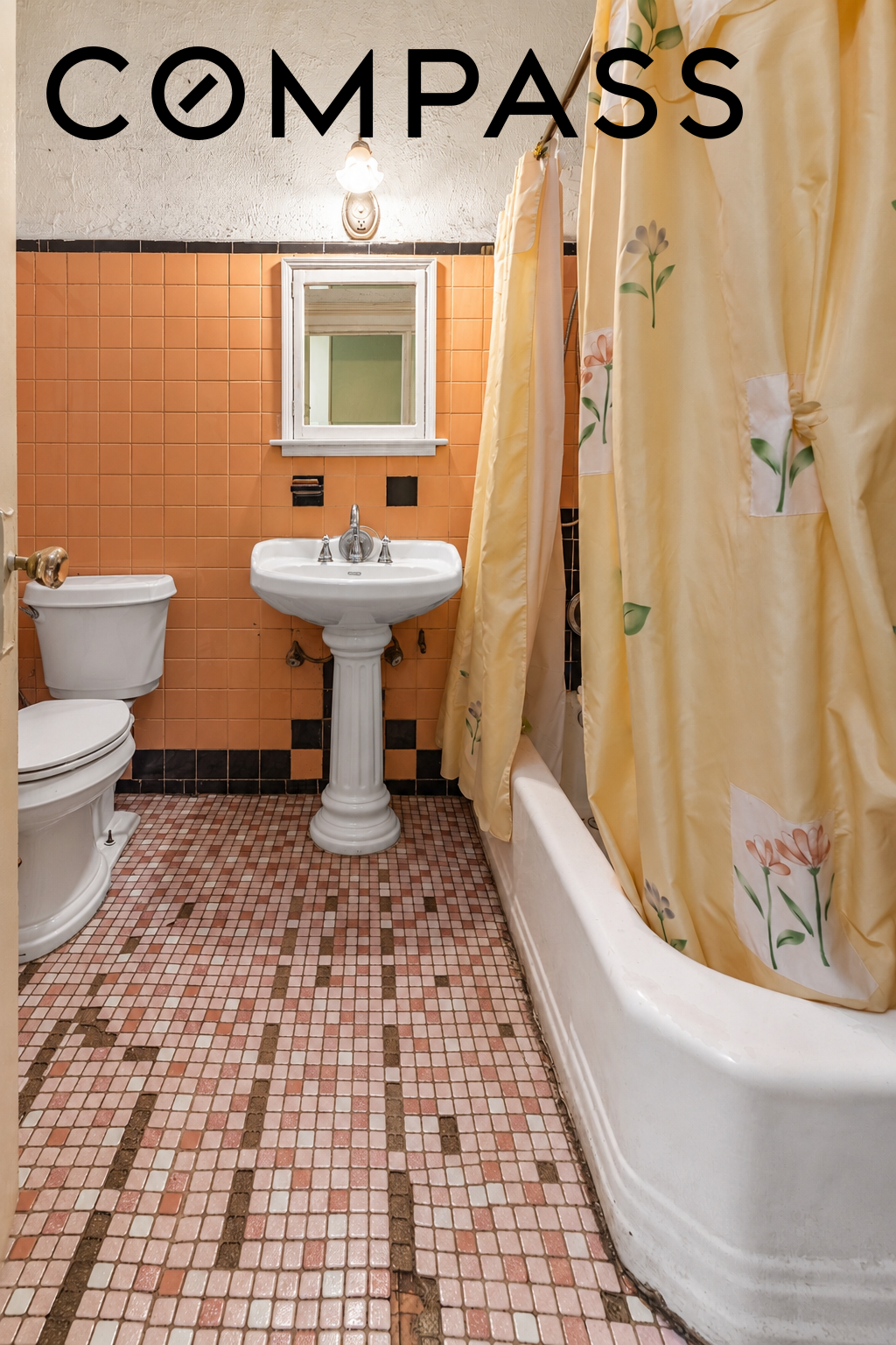 Bathroom with orange wall tiles, a pedestal sink, and a white tub behind a floral shower curtain.