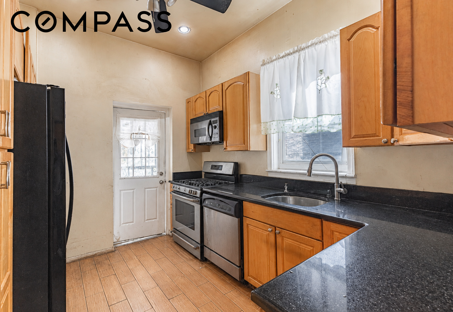 Kitchen with honey-colored cabinets, dark counters, stainless appliances, and a peninsula.