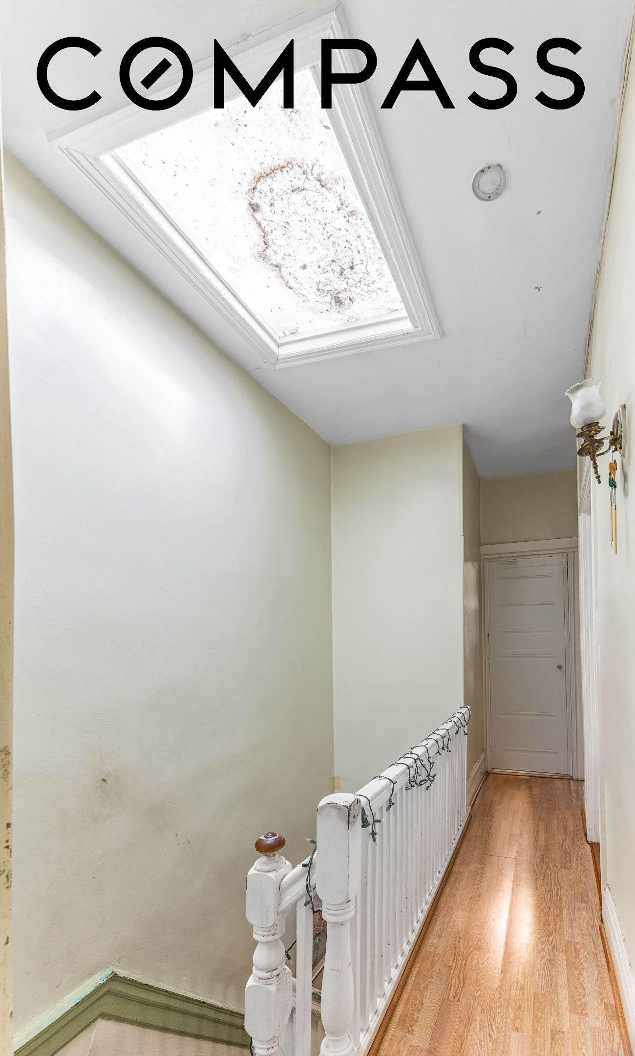 Hallway with a large skylight, wood flooring, and a white stair railing.