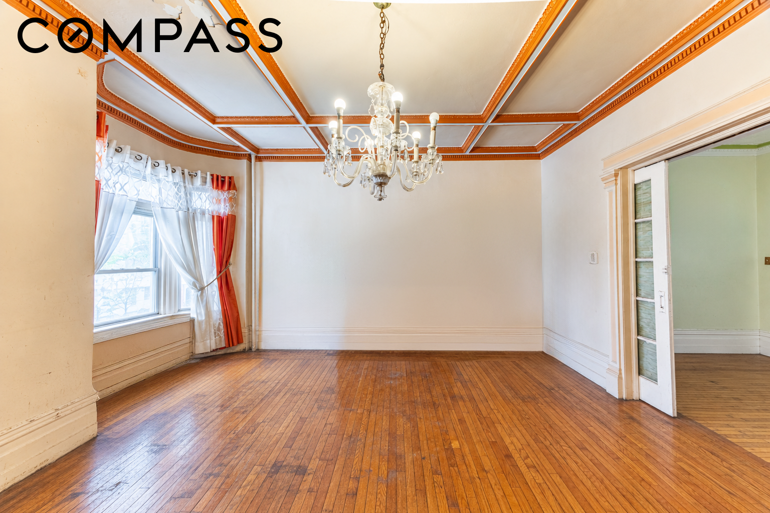 Vacant formal dining room with a chandelier, ornate coffered ceiling, and polished hardwood floors.