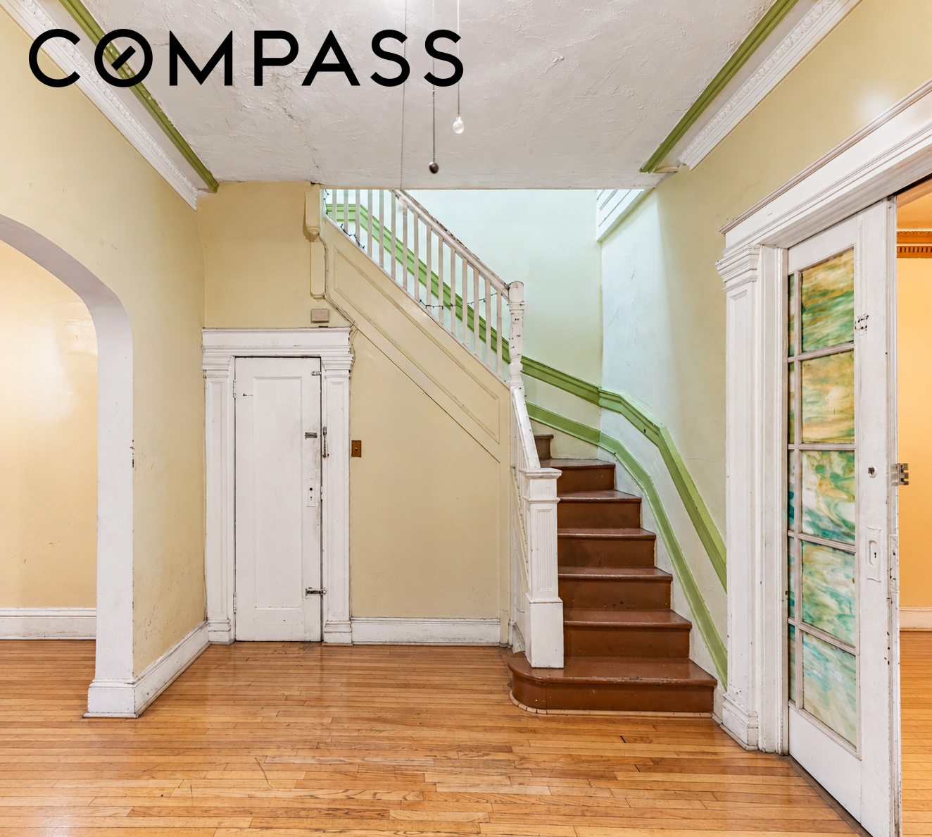 Entry foyer with hardwood floors, a curved staircase, and ornate white woodwork.