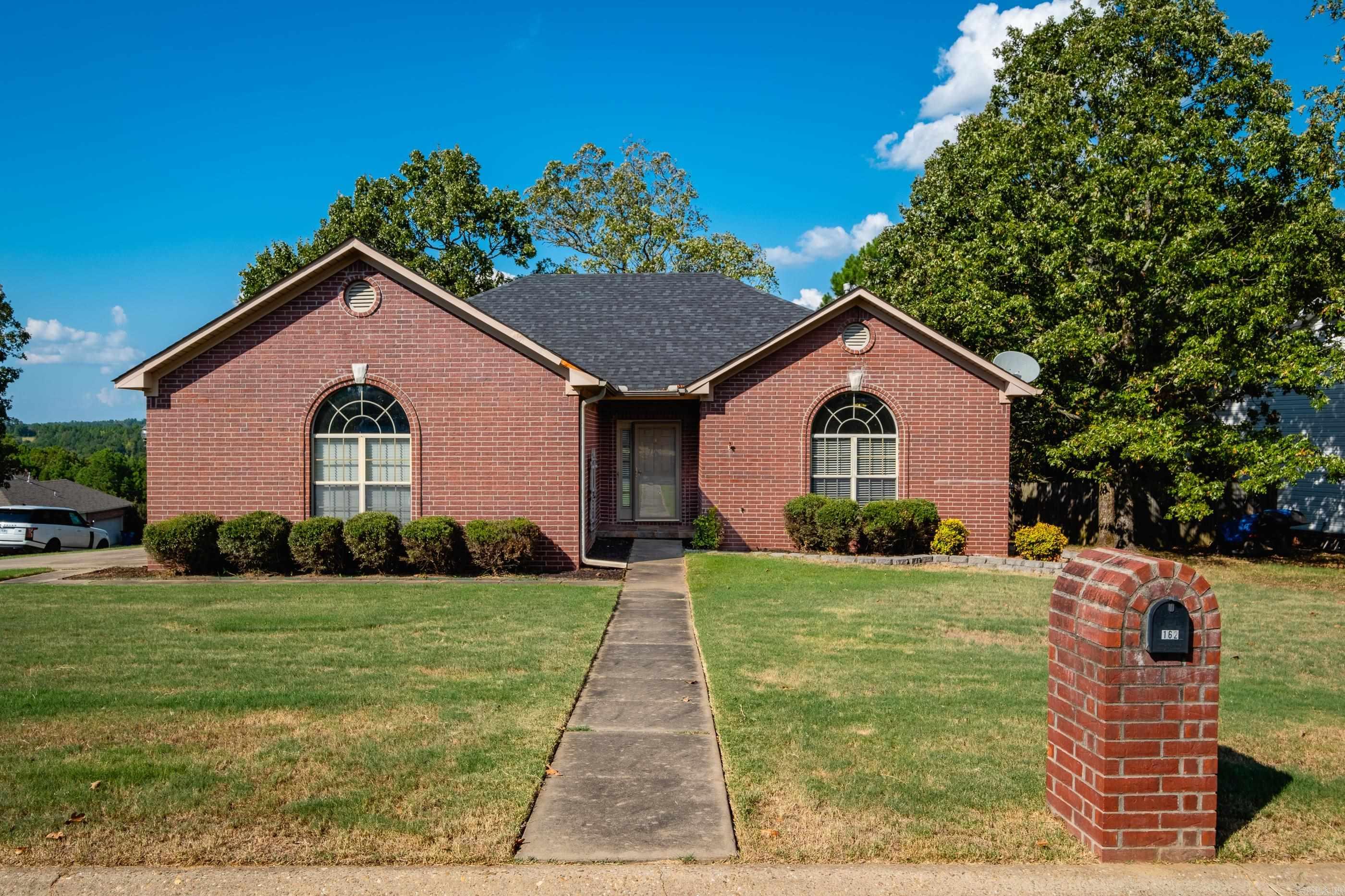 Red brick house with arched windows, a front lawn, and a brick mailbox marked 162.