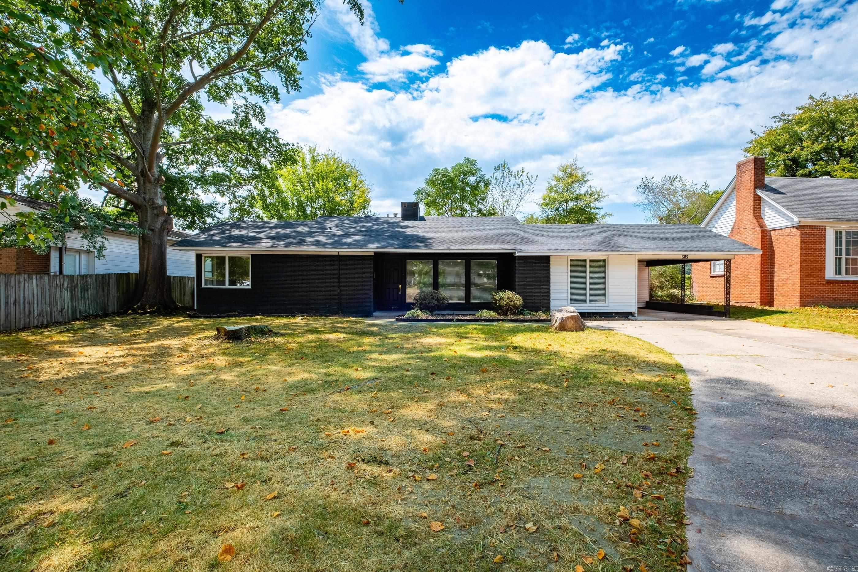 Single-story ranch house with dark brick, white siding, and a covered carport beside a broad lawn.