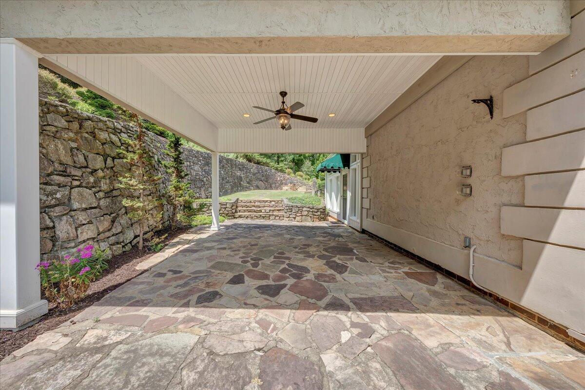 Covered flagstone patio with a ceiling fan and stone garden walls.