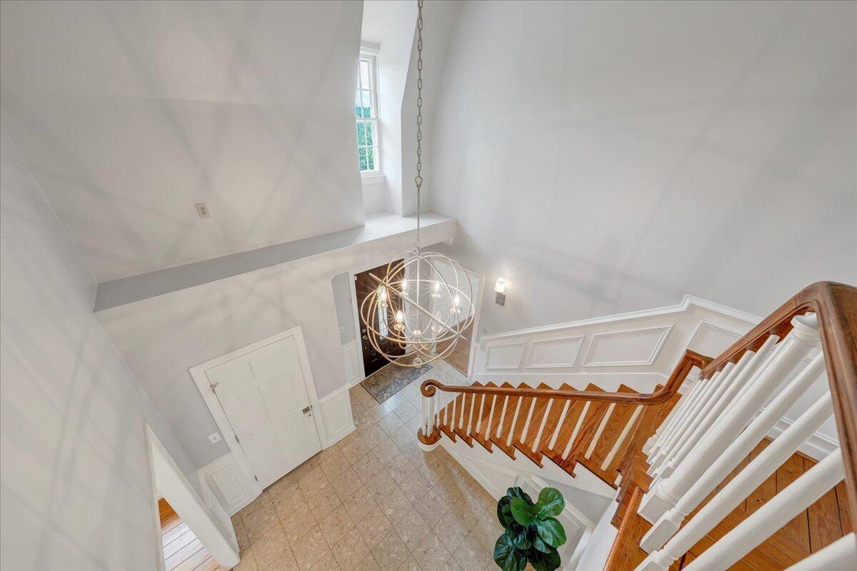 Two-story foyer with a curved wood staircase, white balusters, and a spherical chandelier.