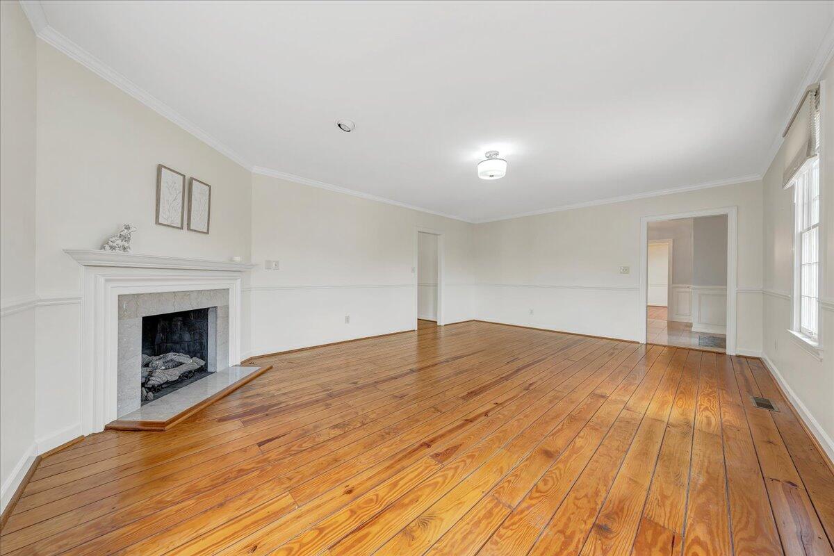 Empty living room with a stone fireplace and polished hardwood floors.