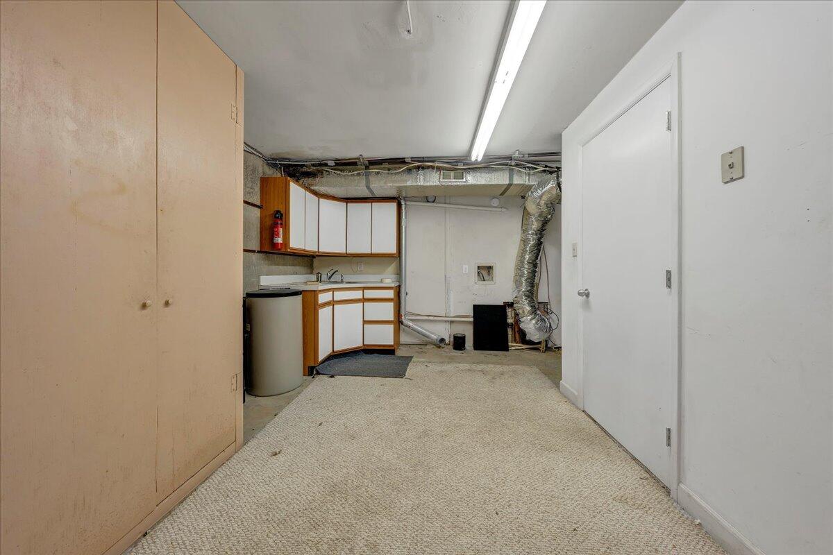 Basement utility room with built-in cabinets, a sink, and exposed HVAC ductwork.