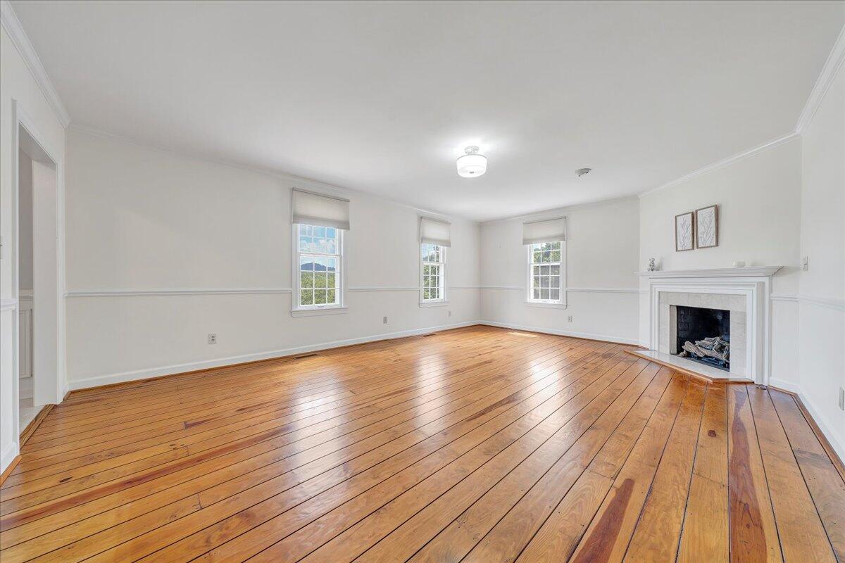 Vacant living room with polished hardwood floors and a white fireplace.